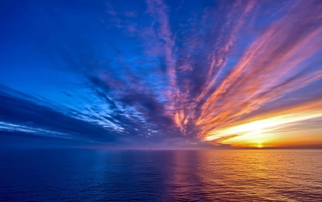 Colorful Sunset 桌布 壁紙 — 令人嘆為觀止的海上日落，從地平線散發出充滿活力的橙色和紫色雲彩。