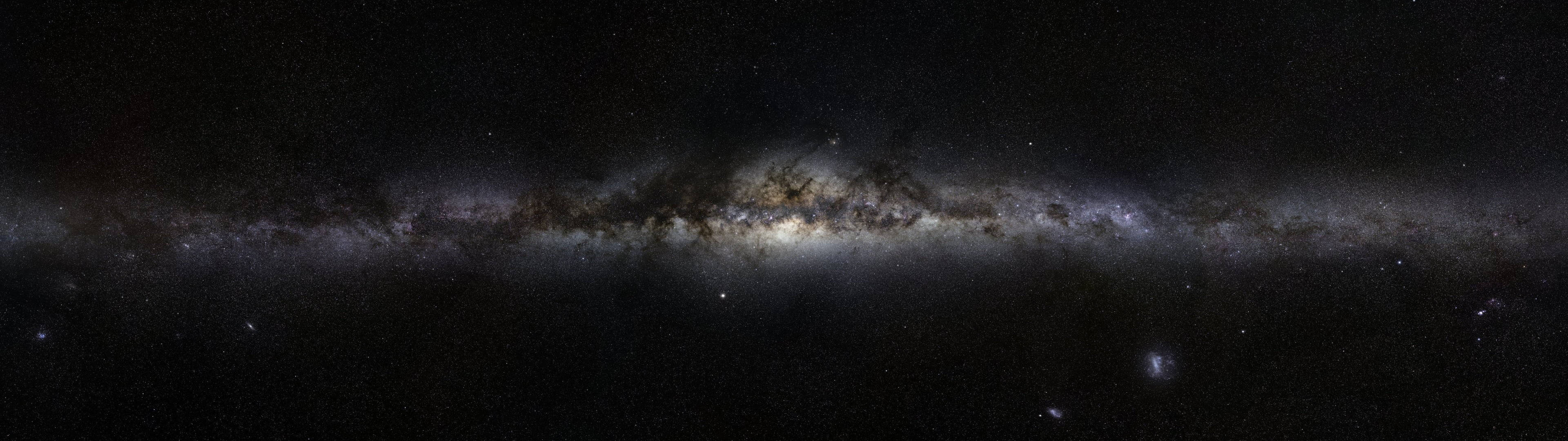 銀河系在佈滿星星的夜空中帶有發光的星雲和黑暗的塵埃帶。