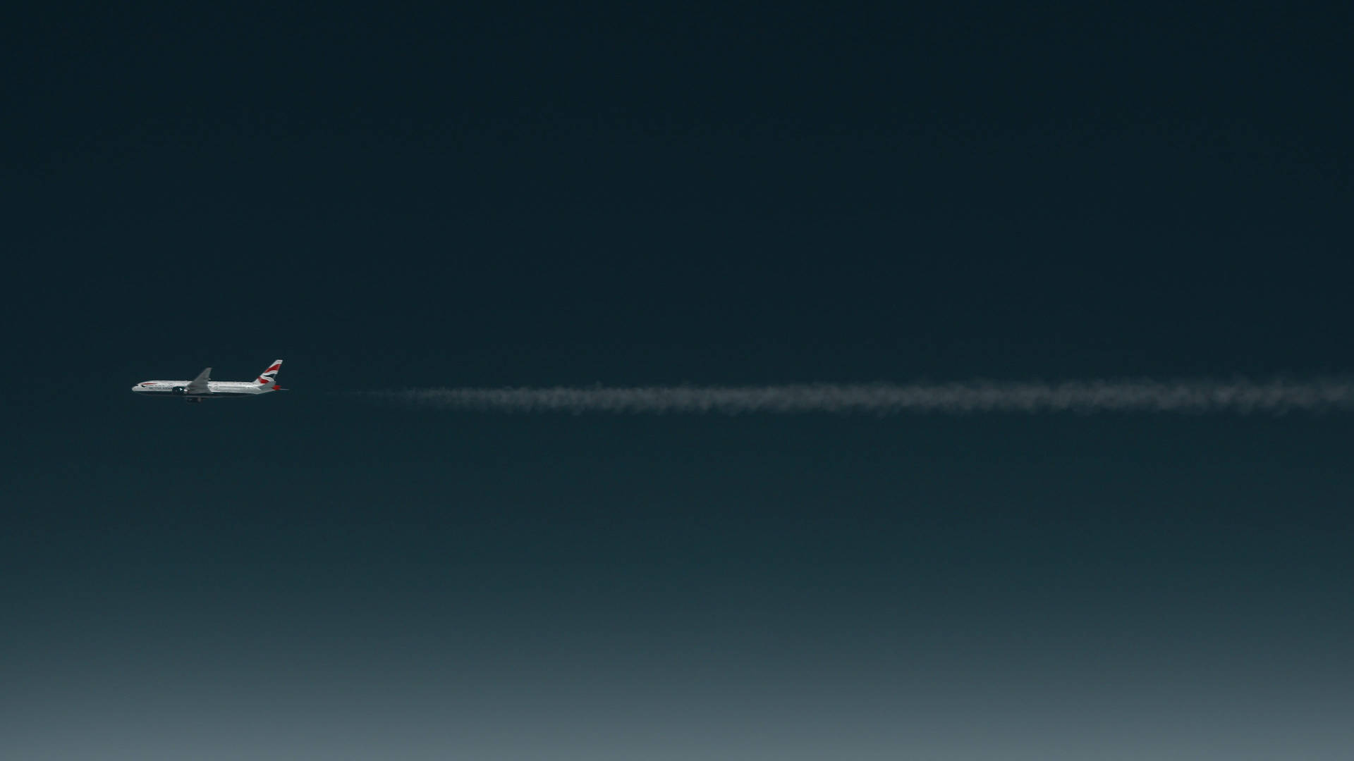 一架英國航空公司的飛機在深藍色的天空中高高飛翔，留下一條長長的白線。