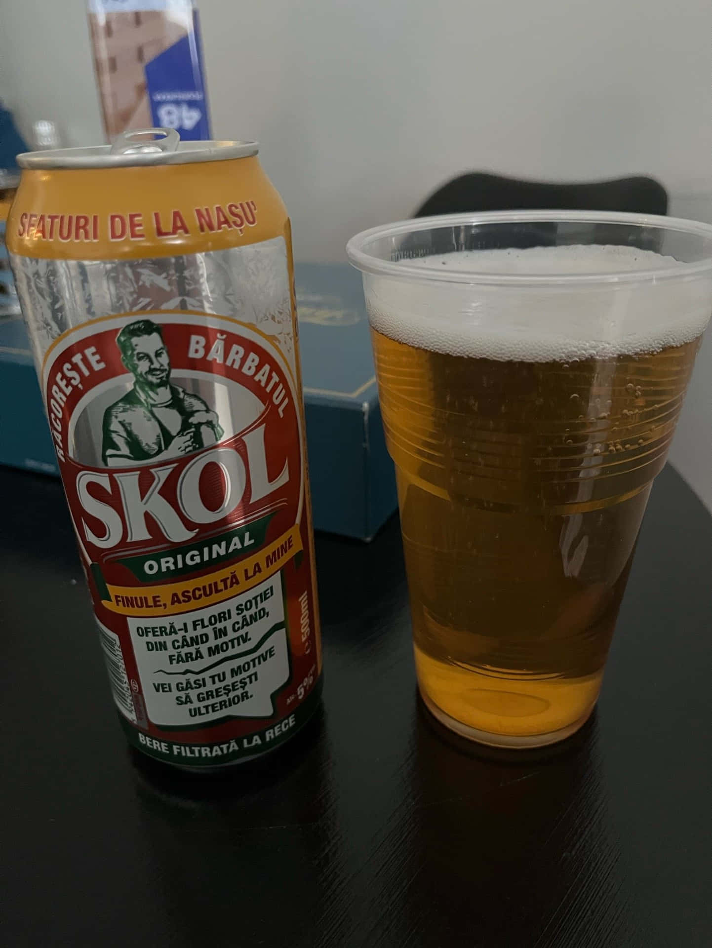  壁紙 — 一罐Skol啤酒和一個泡沫豐富的玻璃杯並排放在昏暗的桌子上，營造出休閒的室內氛圍。