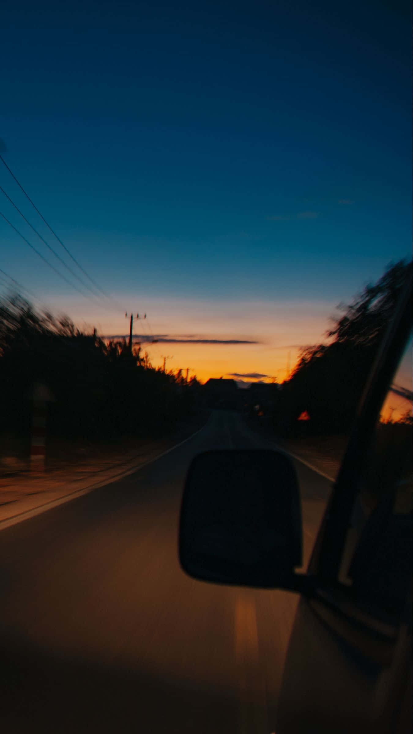 Sunset Drive 桌布 壁紙 — 汽車側鏡反射出一條黃昏道路，橙色天空逐漸褪變成深藍色。