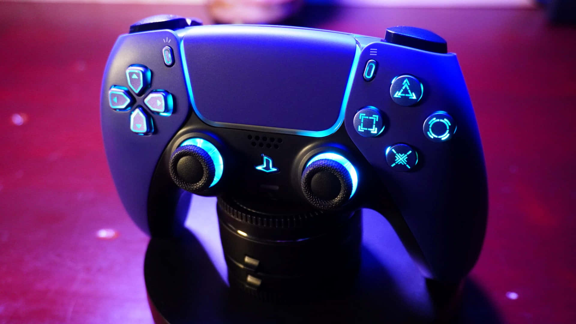  壁紙 — PlayStation 5 手掣嘅特寫，喺深紅色背景上發出鮮豔嘅藍光。