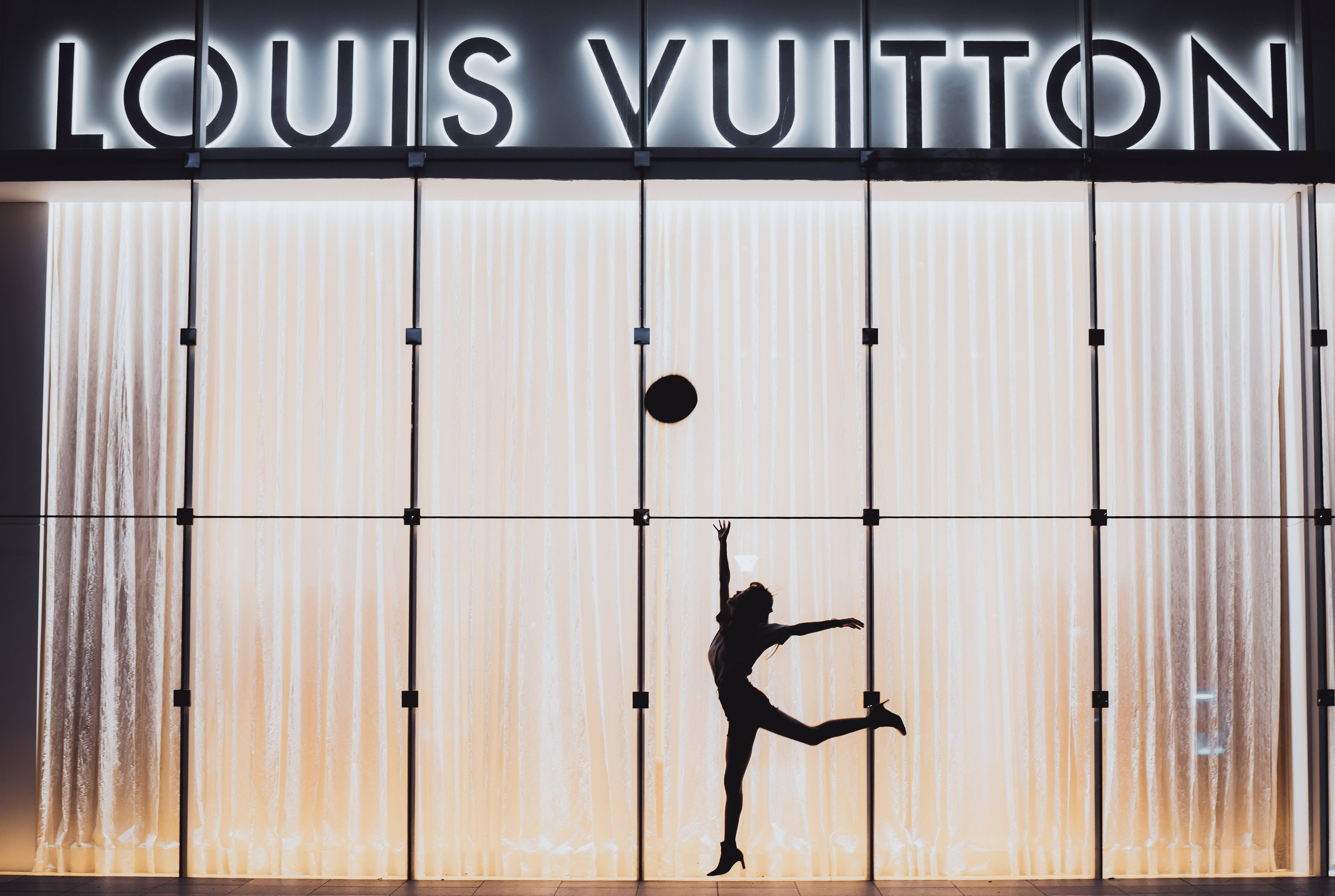 夜晚在 Louis Vuitton 商店前跳躍的舞者剪影。 — 路易威登 壁紙