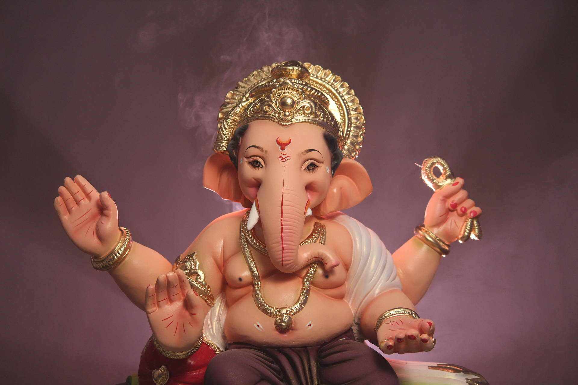 象頭神像飾有金色珠寶和王冠，坐著，身後煙霧升騰。