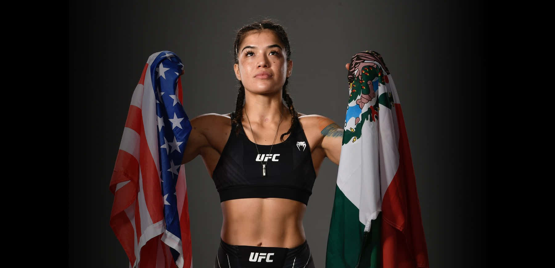  壁紙 — 一位堅定的女性UFC拳手在深色工作室背景下手持美國和墨西哥國旗。