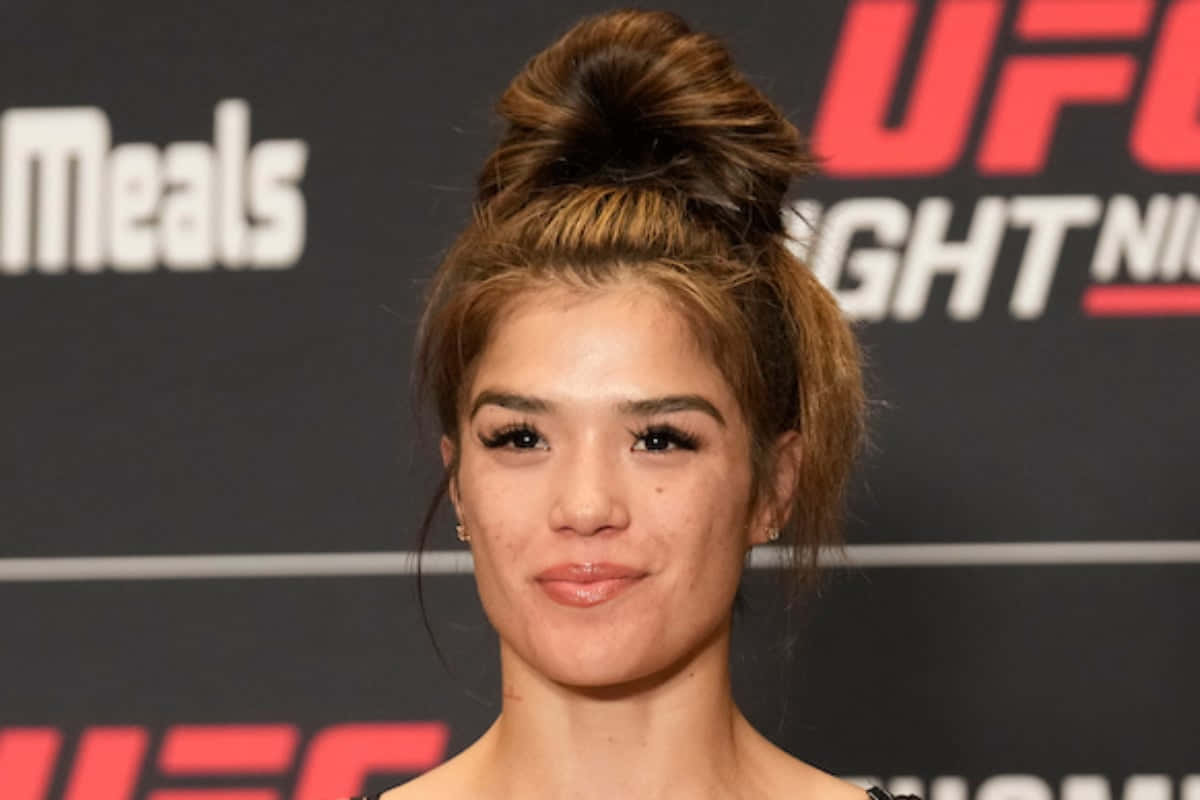  壁紙 — 一位專注的女拳手，梳著高髮髻，在UFC Fight Night背景前擺姿勢。