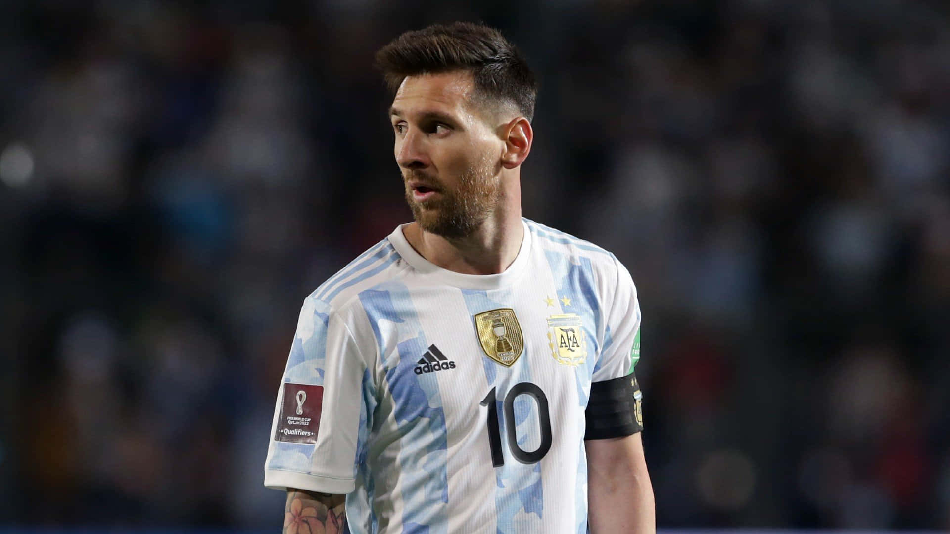 Messi 2022 桌布 壁紙 — 阿根廷足球巨星利昂內爾·美斯身穿標誌性的10號球衣，在球場燈光下的夜間比賽中專注地站立。