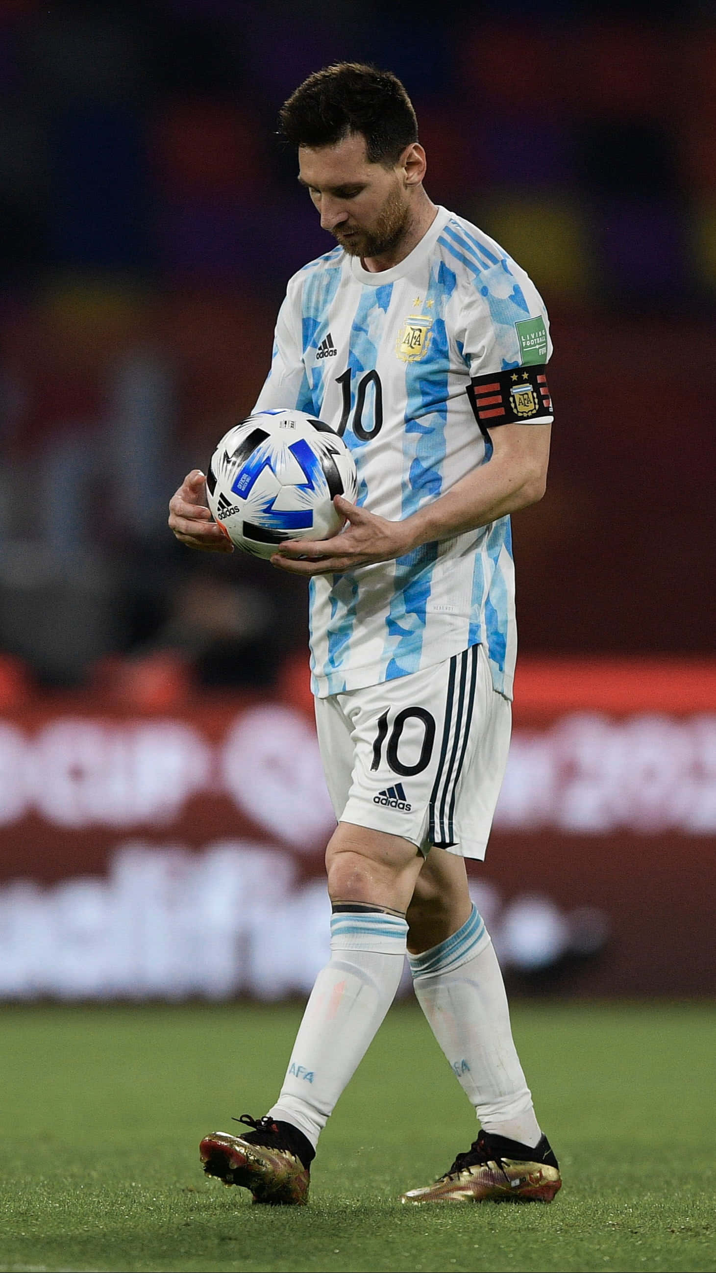 Messi 2022 桌布 壁紙 — 阿根廷足球巨星美斯身穿藍白間條球衣，在明亮的燈光下於球場上手持足球。