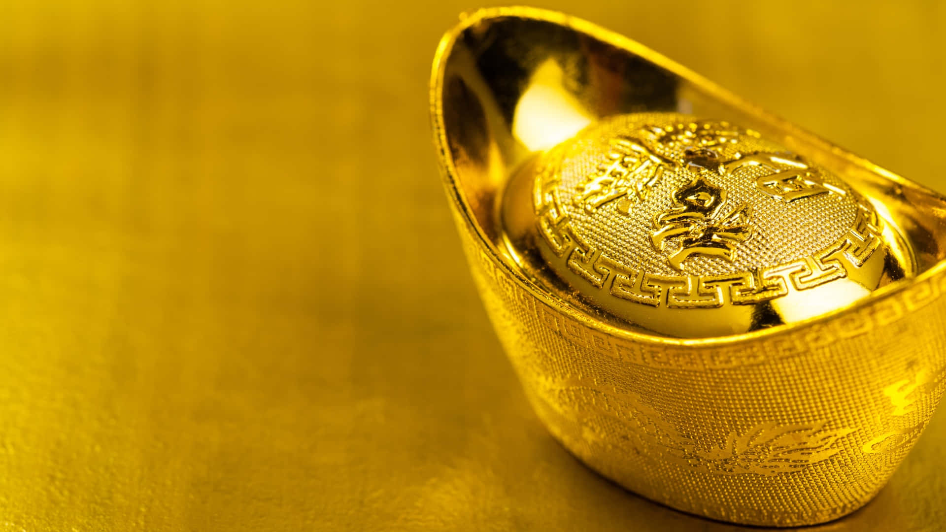  壁紙 — 閃亮的傳統金條在溫暖燈光下放置於有紋理的金色表面上。