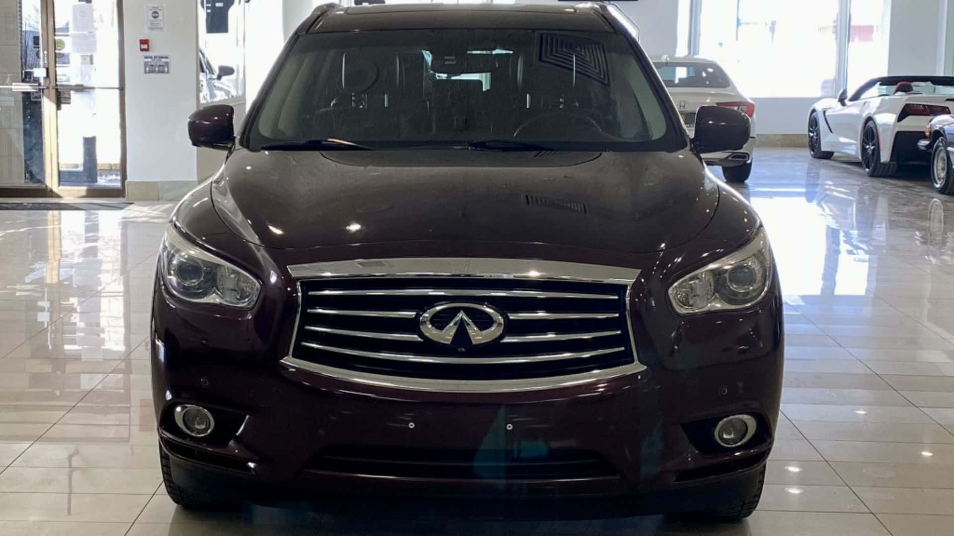 Infiniti Jx35 桌布 壁紙 — 一輛亮面栗色Infiniti SUV在明亮的汽車經銷商展廳中向前，地板鋪有瓷磚，其他車輛可見。