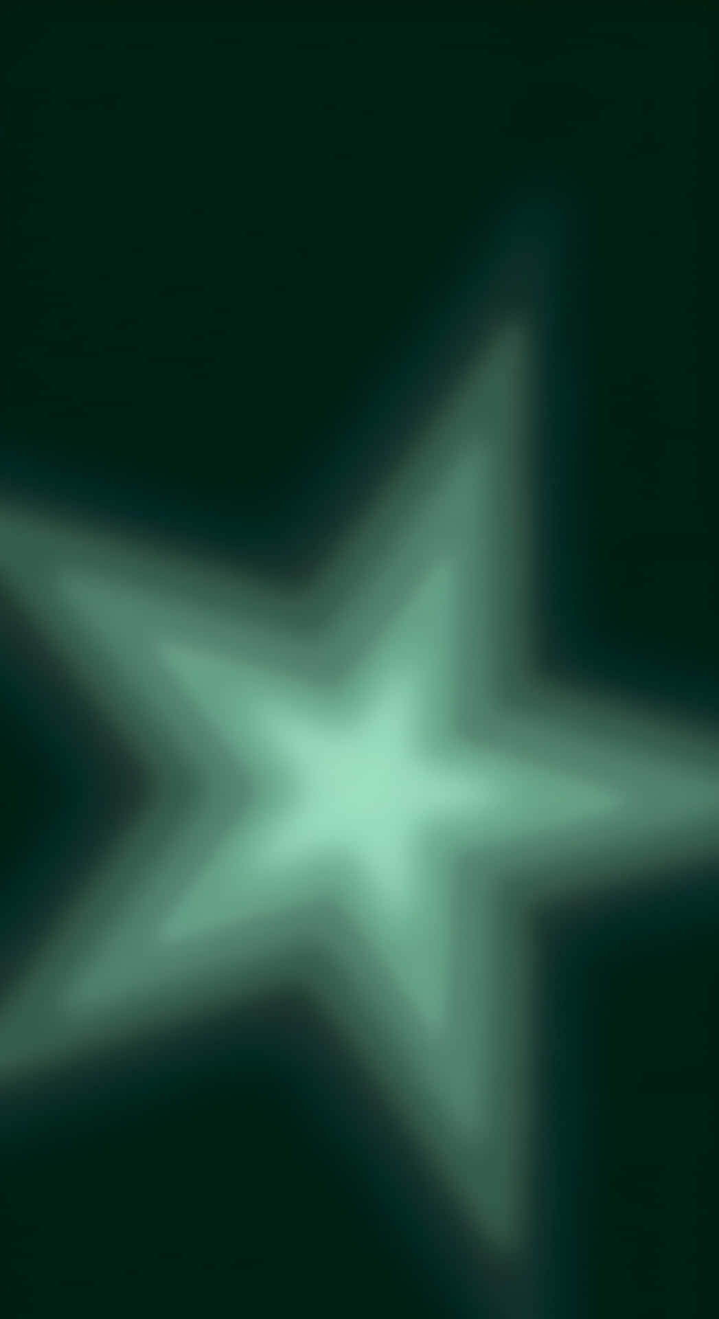  壁紙 — 一顆發光的綠色星星在黑暗背景上散發出柔和的光芒，帶有模糊、夢幻的效果。