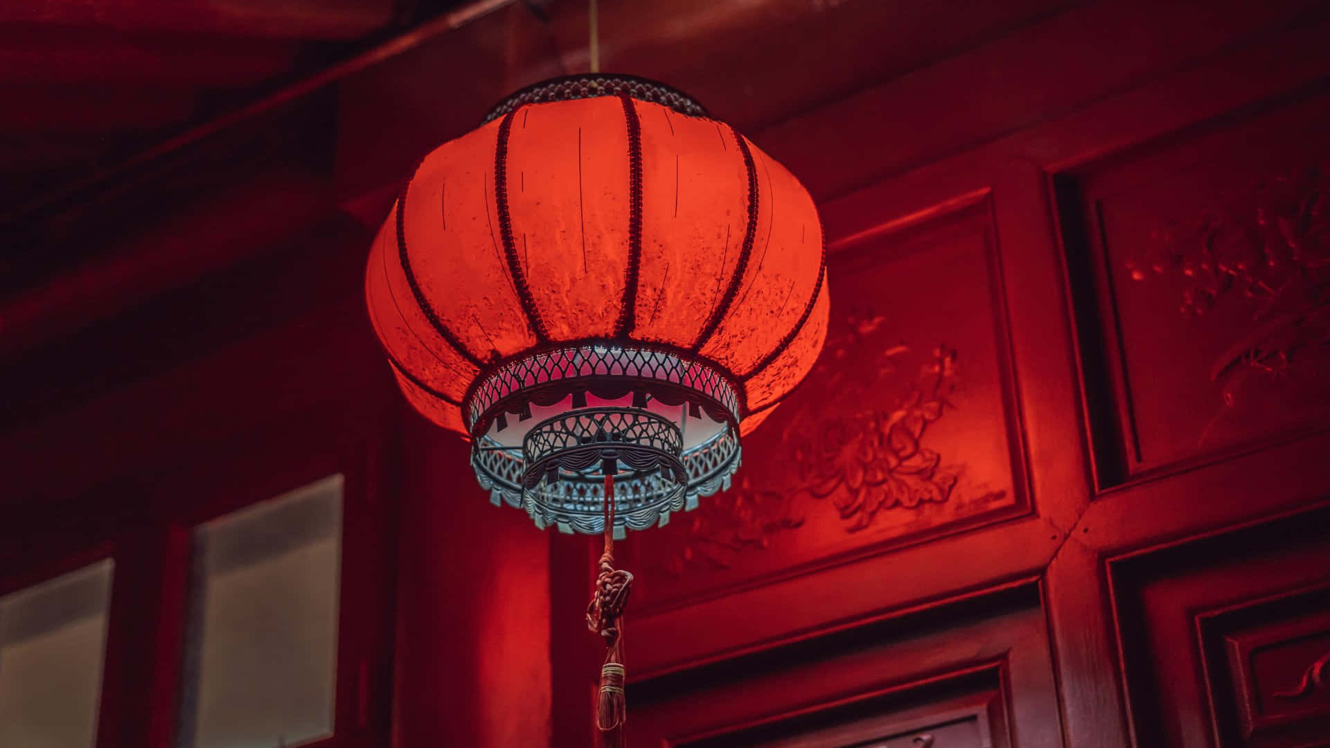  壁紙 — 一個發光的紅色紙燈籠，帶有黑色邊框，掛在溫暖環境光沐浴的華麗木板上。