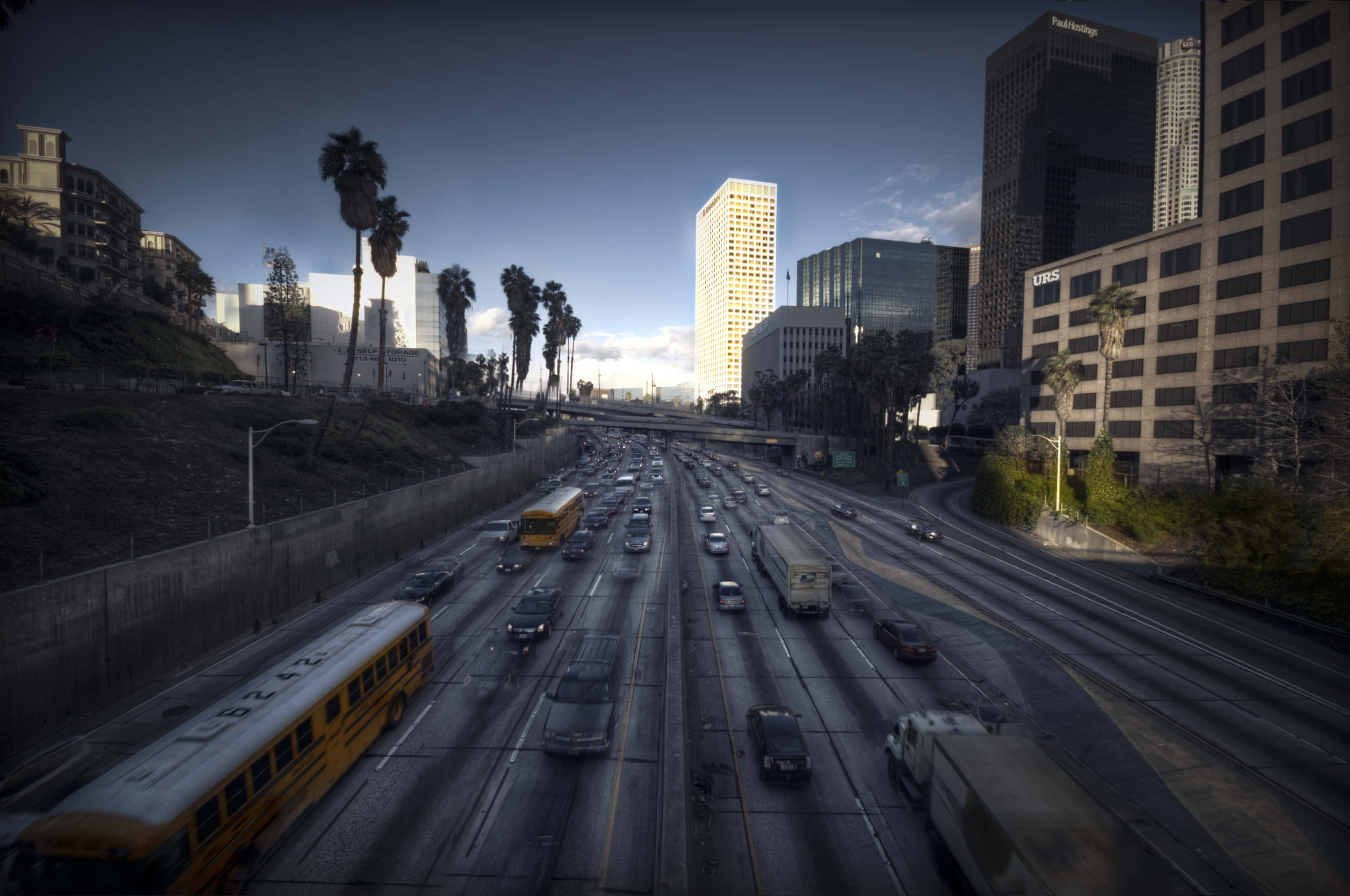 La 桌布 壁紙 — 黃昏時分繁忙城市高速公路的高角度景觀，棕櫚樹和摩天大樓沿路排列。