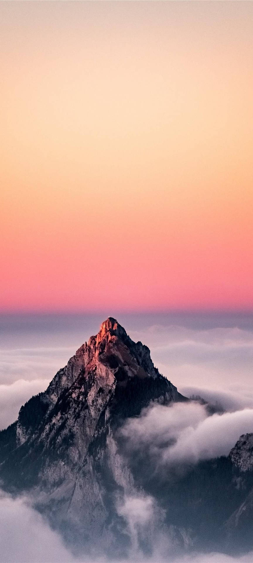 日出時山峰聳立於雲層之上，天空呈現粉紅與橙色。