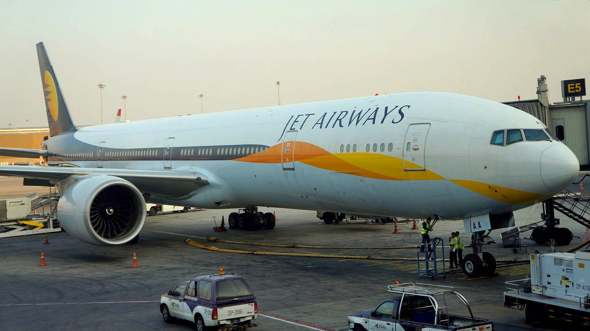 Jet Airways飛機停泊在機場閘口，有地勤人員和服務車輛。 — 飛機 壁紙