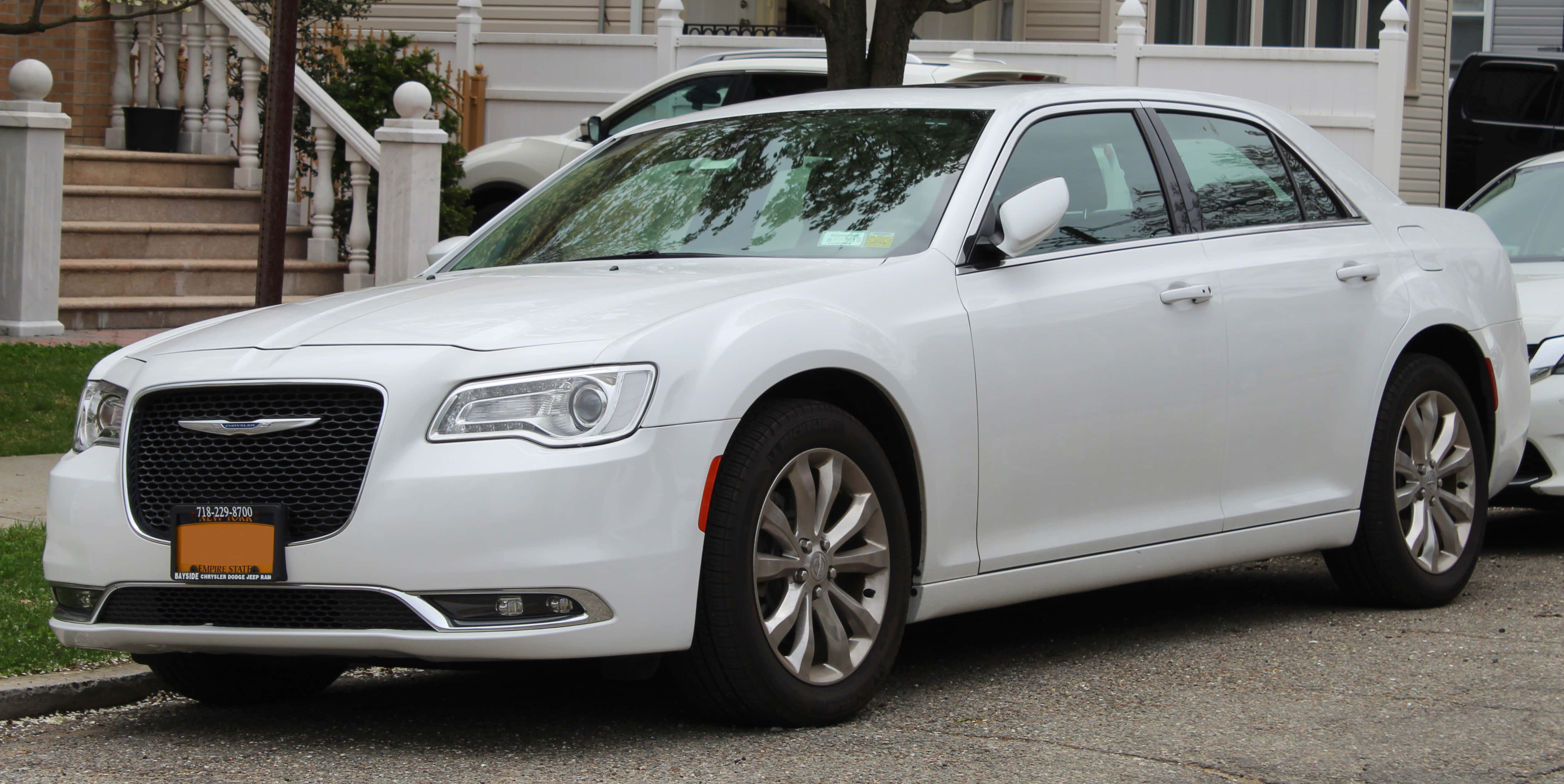 Chrysler 300 桌布 壁紙 — 一架純白色嘅克萊斯勒房車停泊喺住宅街道上，背景有間屋同樓梯。