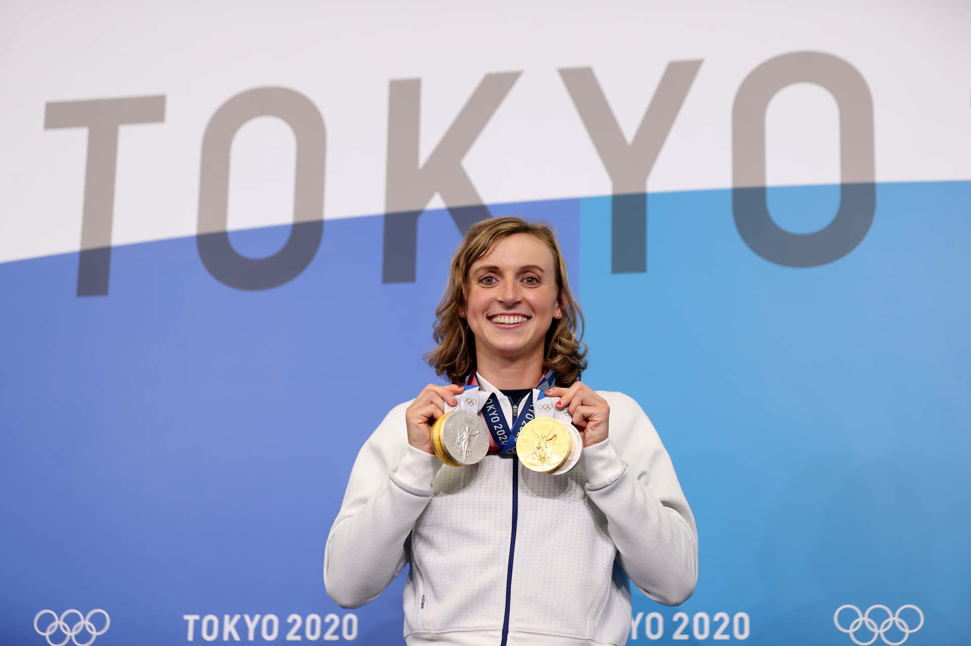  壁紙 — 一位快樂的女泳手在東京2020背景下自豪地展示她的三枚奧運獎牌，笑容燦爛。