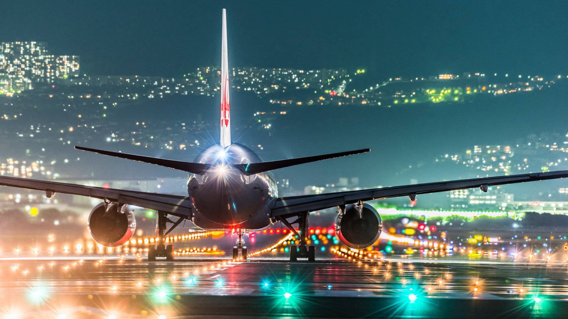 夜間濕滑跑道上的飛機，背景有城市燈光 — 飛機 壁紙