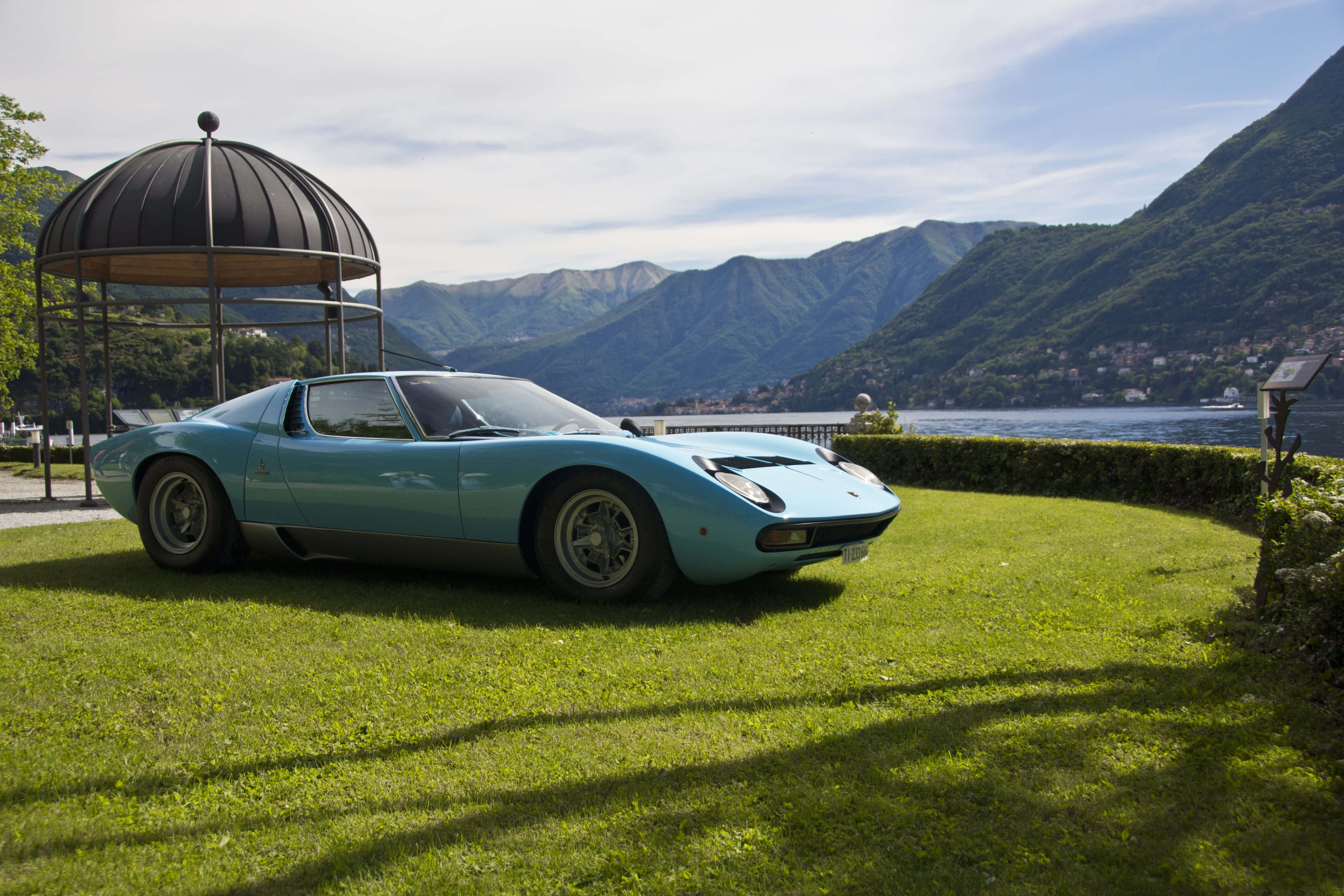Lamborghini Miura 桌布 壁紙 — 一架淺藍色經典林寶堅尼Miura停泊在湖邊草地上，背景有山巒。