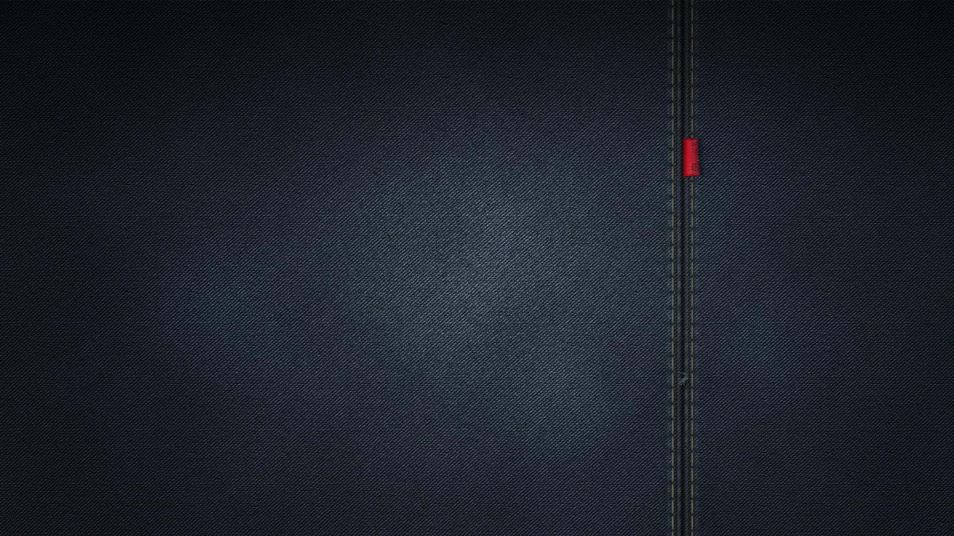 一輛紅色汽車沿著縫在深色牛仔布上的道路行駛。