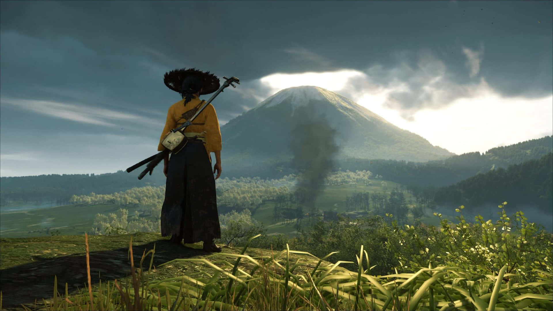  壁紙 — 一個孤獨的武士穿著傳統服裝，站在長滿草的山丘上，俯瞰著戲劇性多雲天空下的霧濛濛山脈。
