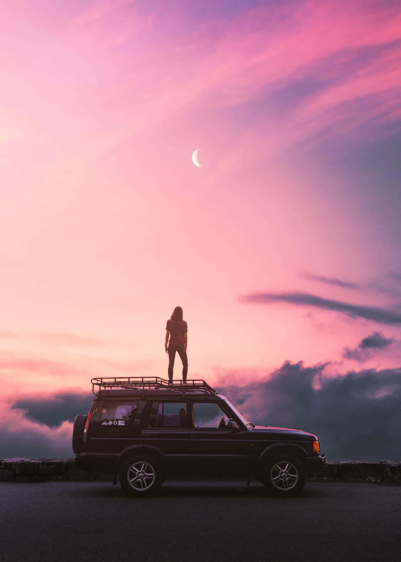 女人在暮色中站在SUV車頂，粉紅天空有新月
