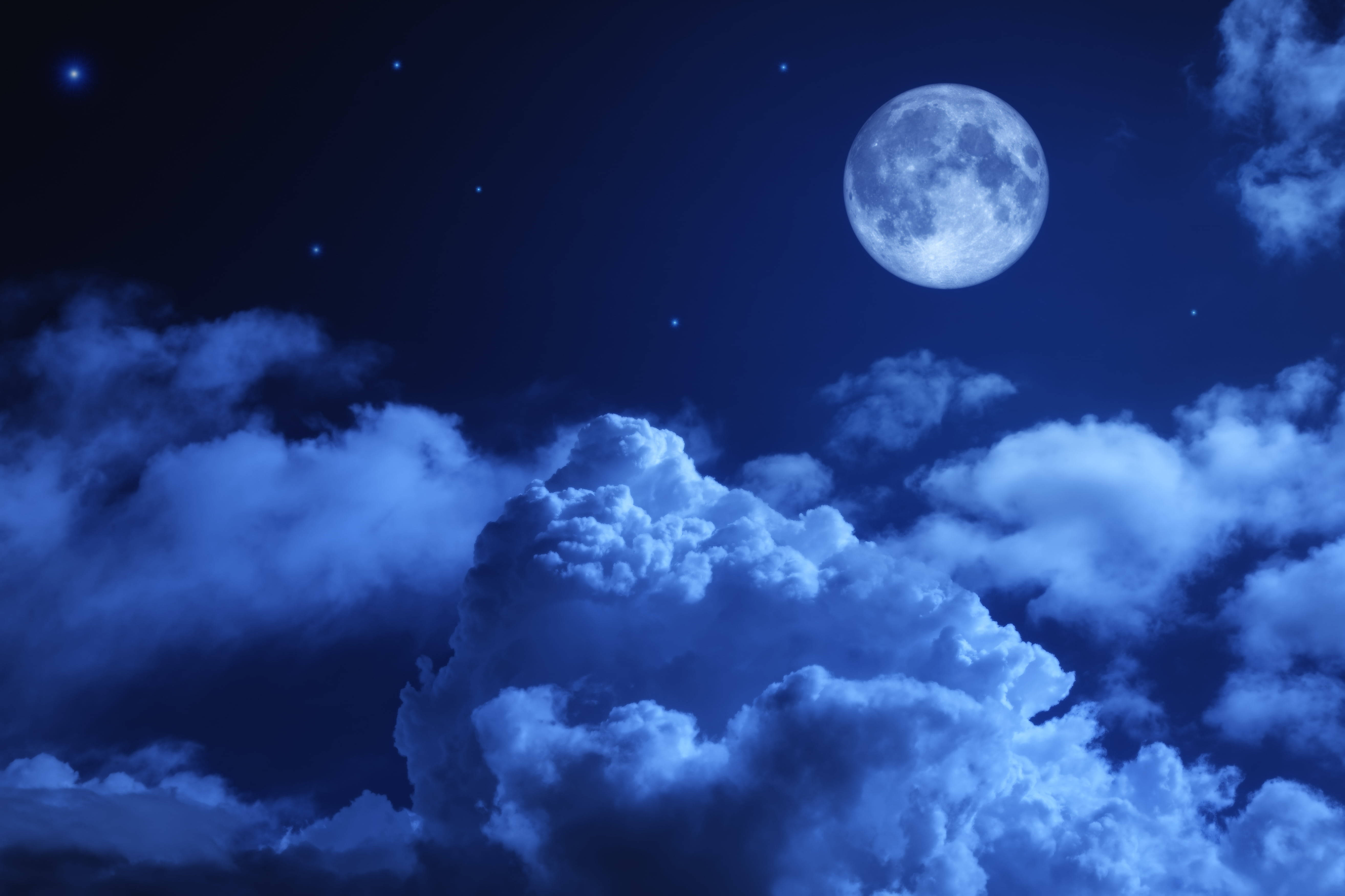滿月在繁星點點的夜空下穿過藍色雲層閃耀。