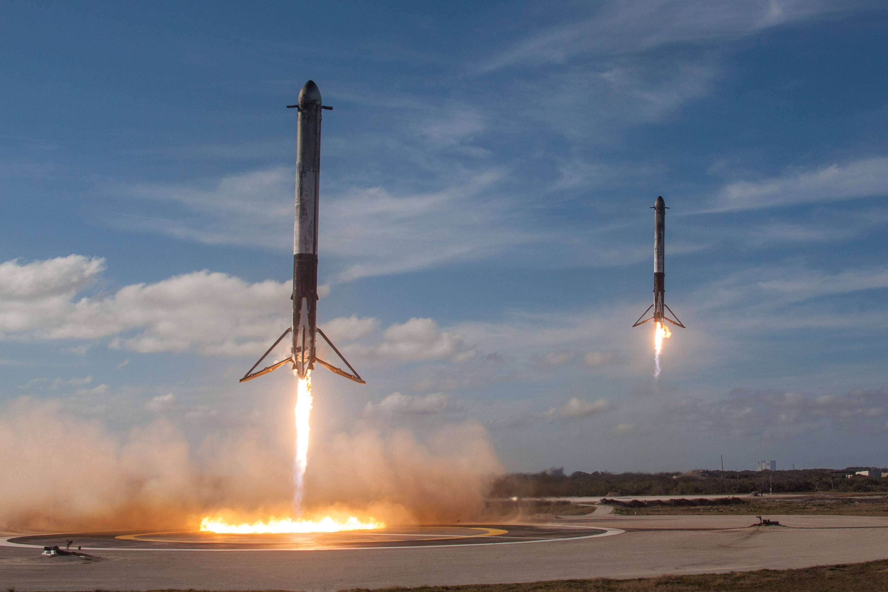 壯觀的 SpaceX 猎鹰 9 号火箭發射 壁紙 — 兩枚火箭在明亮的藍天白雲下從發射台點火升空，噴射出熾熱的推力。