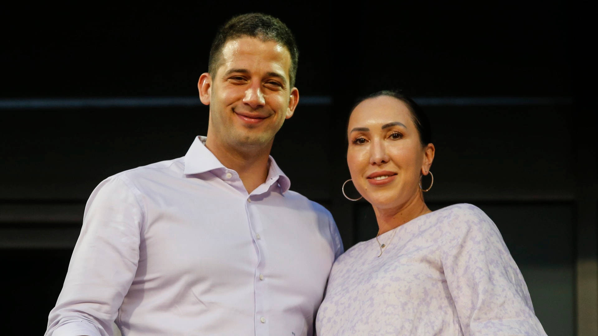 Jelena Janković與丈夫 壁紙 — 一名男子和女子在黑暗的舞台背景下對著鏡頭溫暖微笑。