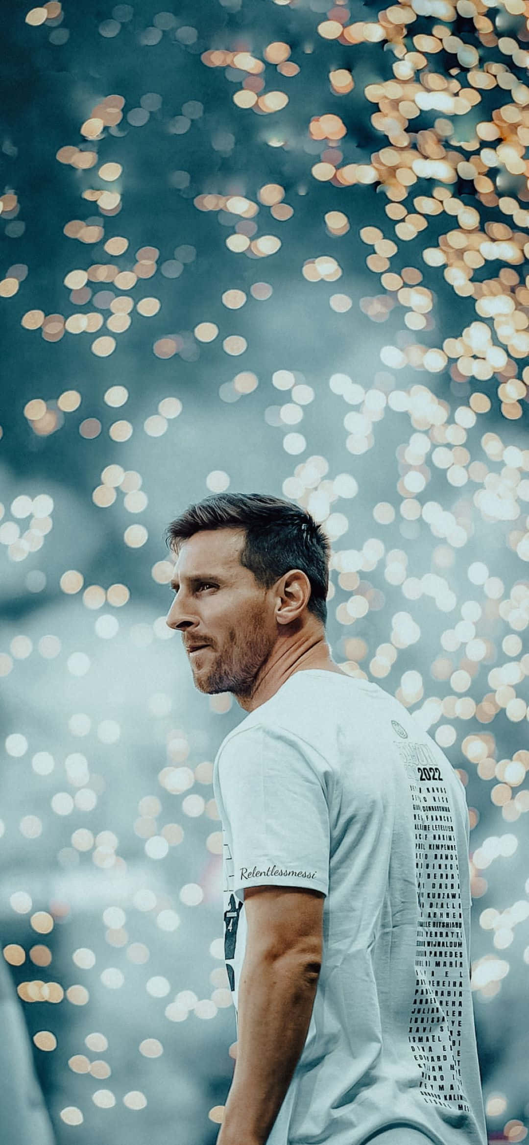 Messi 2022 桌布 壁紙 — 一名身穿淺灰色T恤的男子側身站在發光的金色散景燈光背景下。