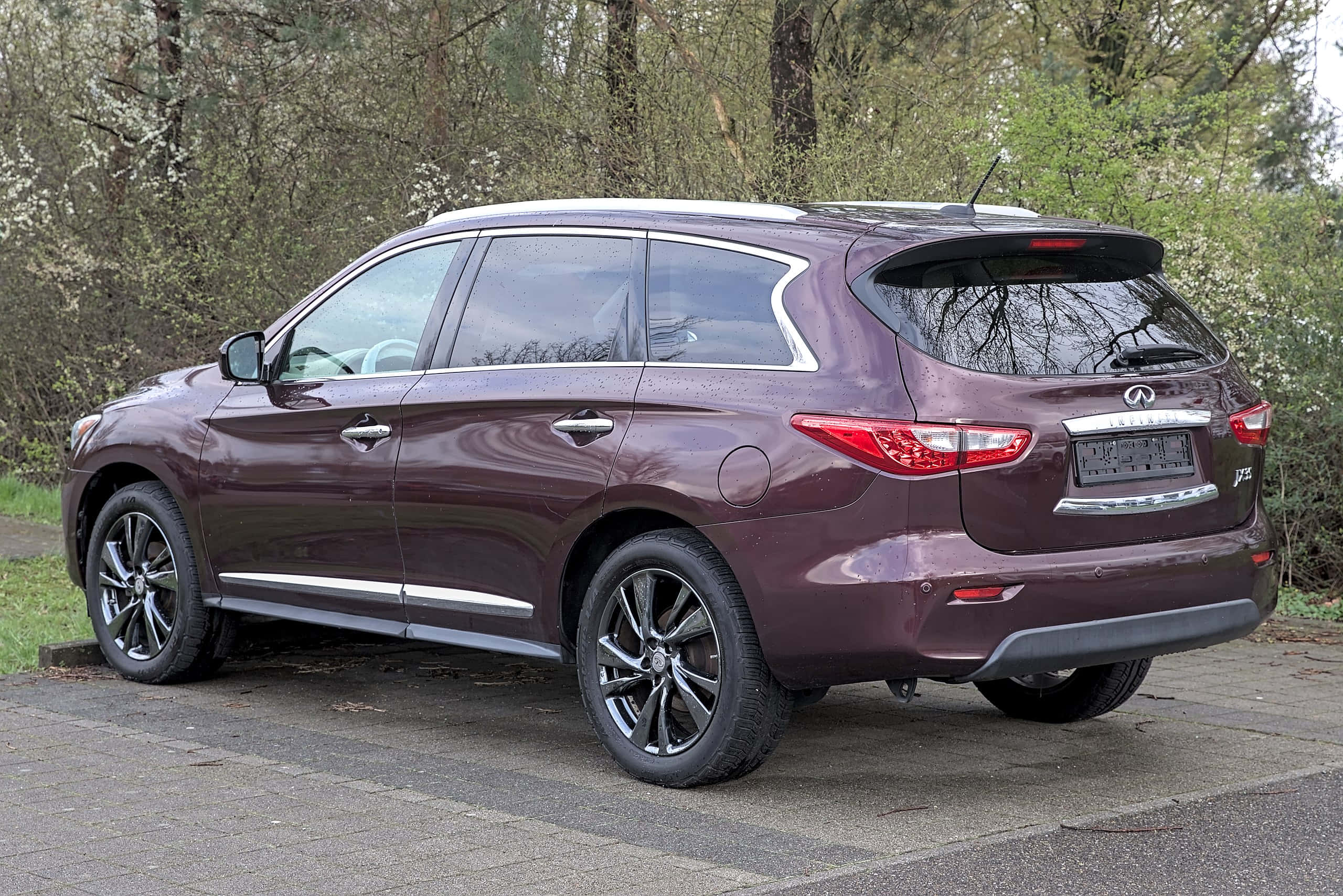 Infiniti Jx35 桌布 壁紙 — 一輛栗色 Infiniti QX60 SUV 停放在鋪砌的車道上，周圍環繞著早春盛開的樹木。