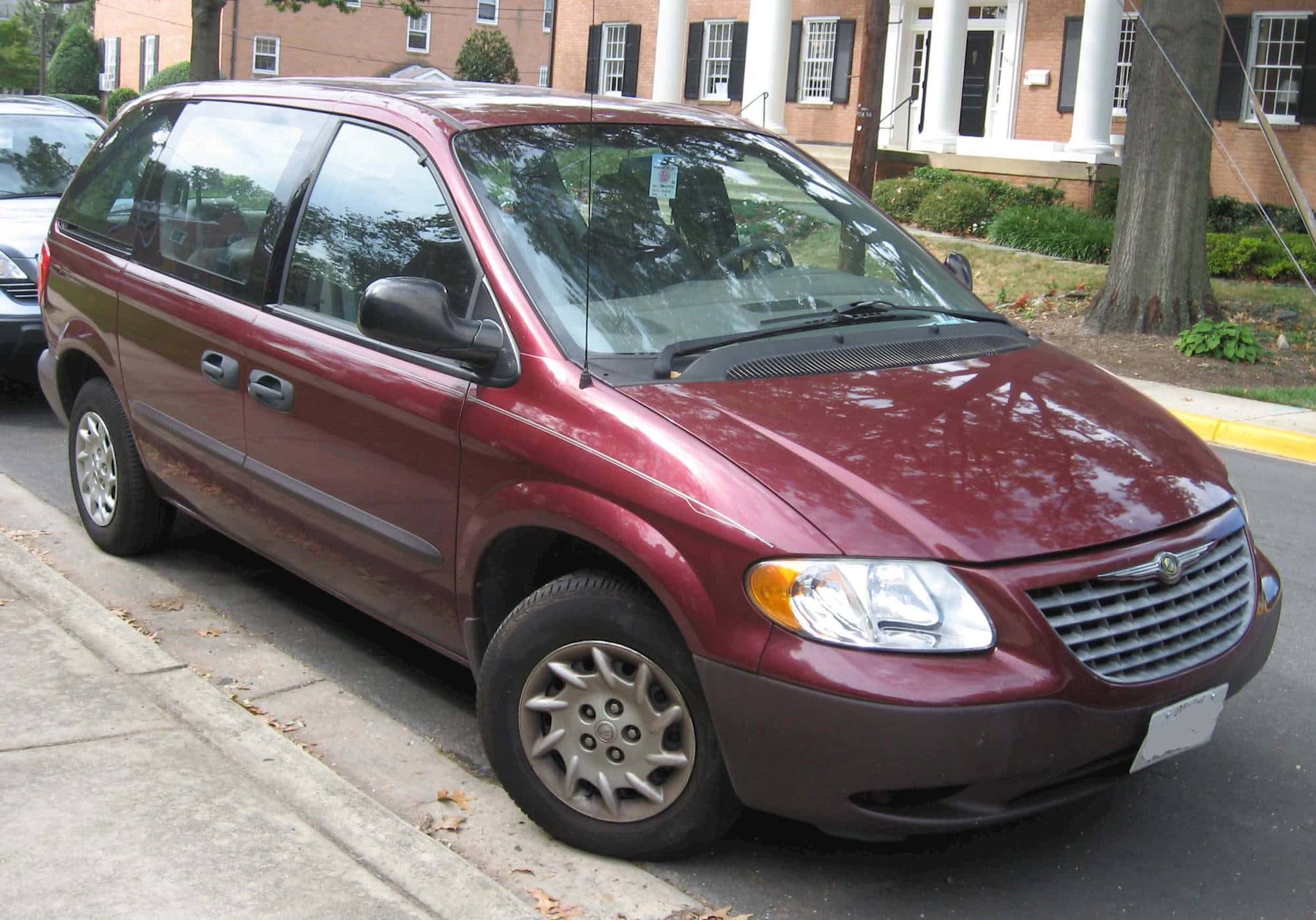 Chrysler Voyager 桌布 壁紙 — 一輛栗色小型貨車停泊在行人路上，旁邊是帶有白色柱子和樹木的磚砌建築。