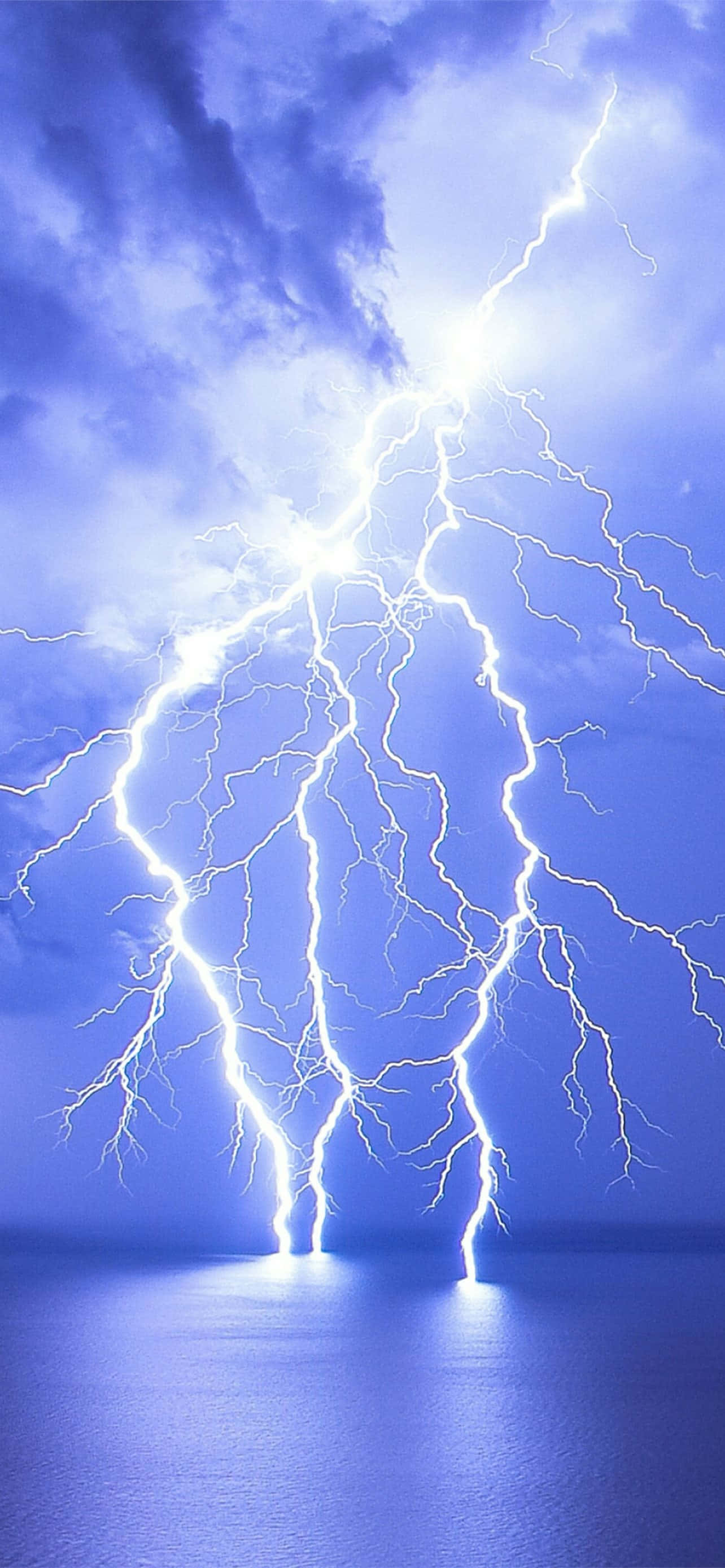 Lightning iPhone 桌布 壁紙 — 一道巨大的閃電從暴風雨的藍色天空中劈下，落入下方平靜的海水中。