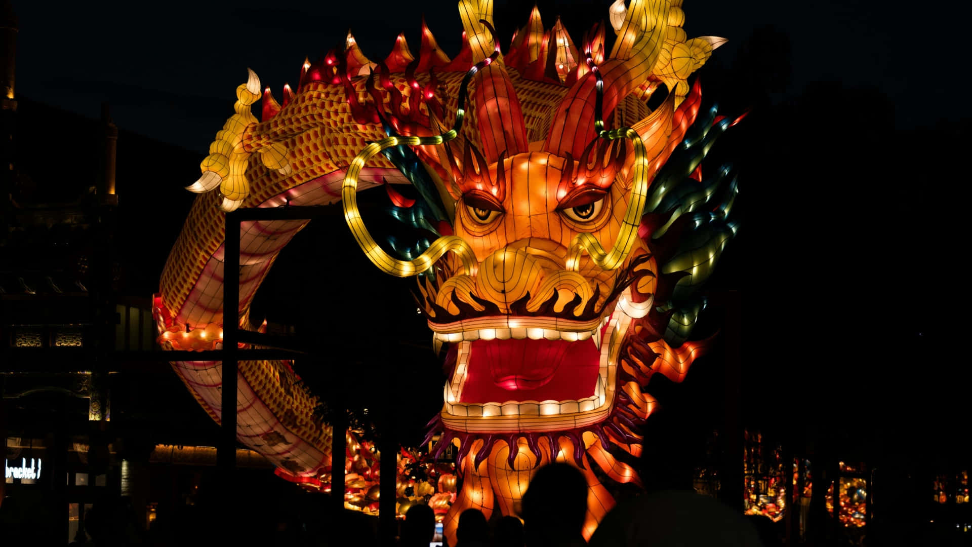  壁紙 — 一個巨大的發光龍燈籠，帶有發光的橙紅色和金色鱗片，主導了夜間節日場景。