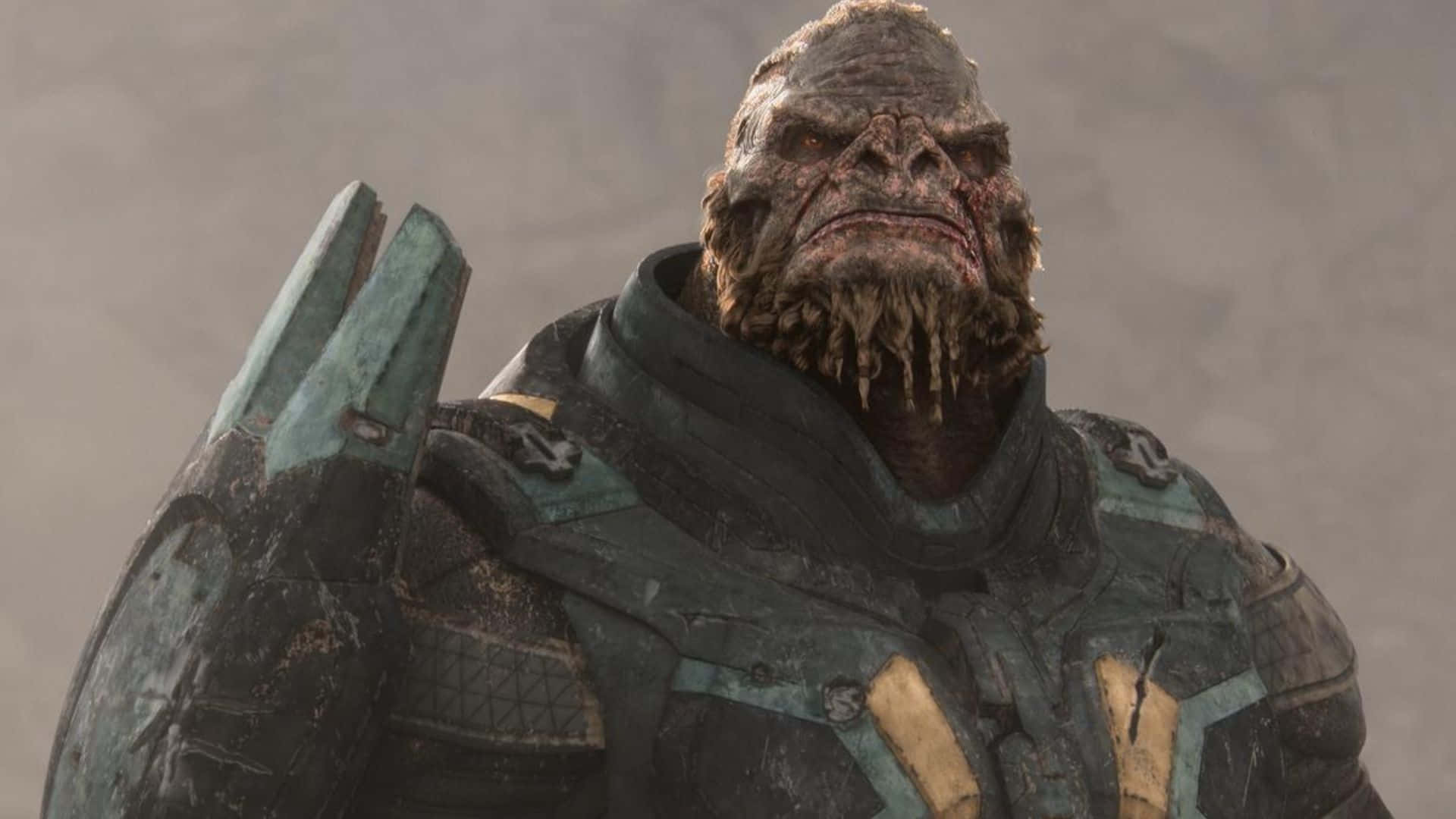 Atriox 桌布 壁紙 — 一個威嚇的外星戰士，身穿風化的綠色和黑色盔甲，在柔和的灰色背景下帶著陰沉的表情站立。