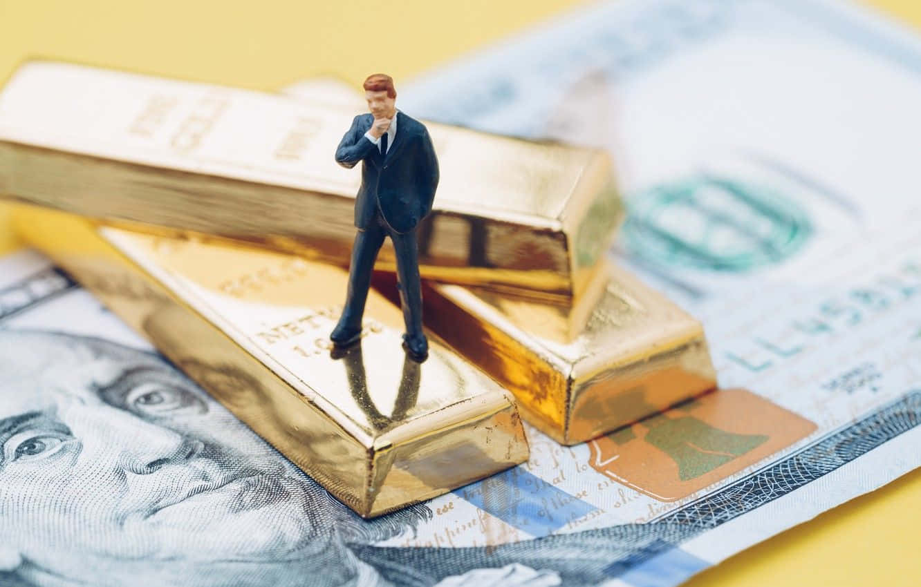 小型商人公仔站在放在美國美元鈔票上的金條上。