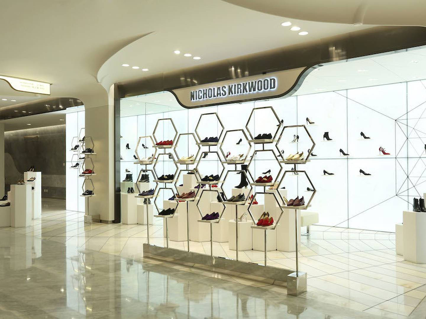 Nicholas Kirkwood 店鋪 壁紙 — 一間現代化的Nicholas Kirkwood鞋店，在明亮的白色牆壁前，用六角形金屬架展示色彩繽紛的高跟鞋。