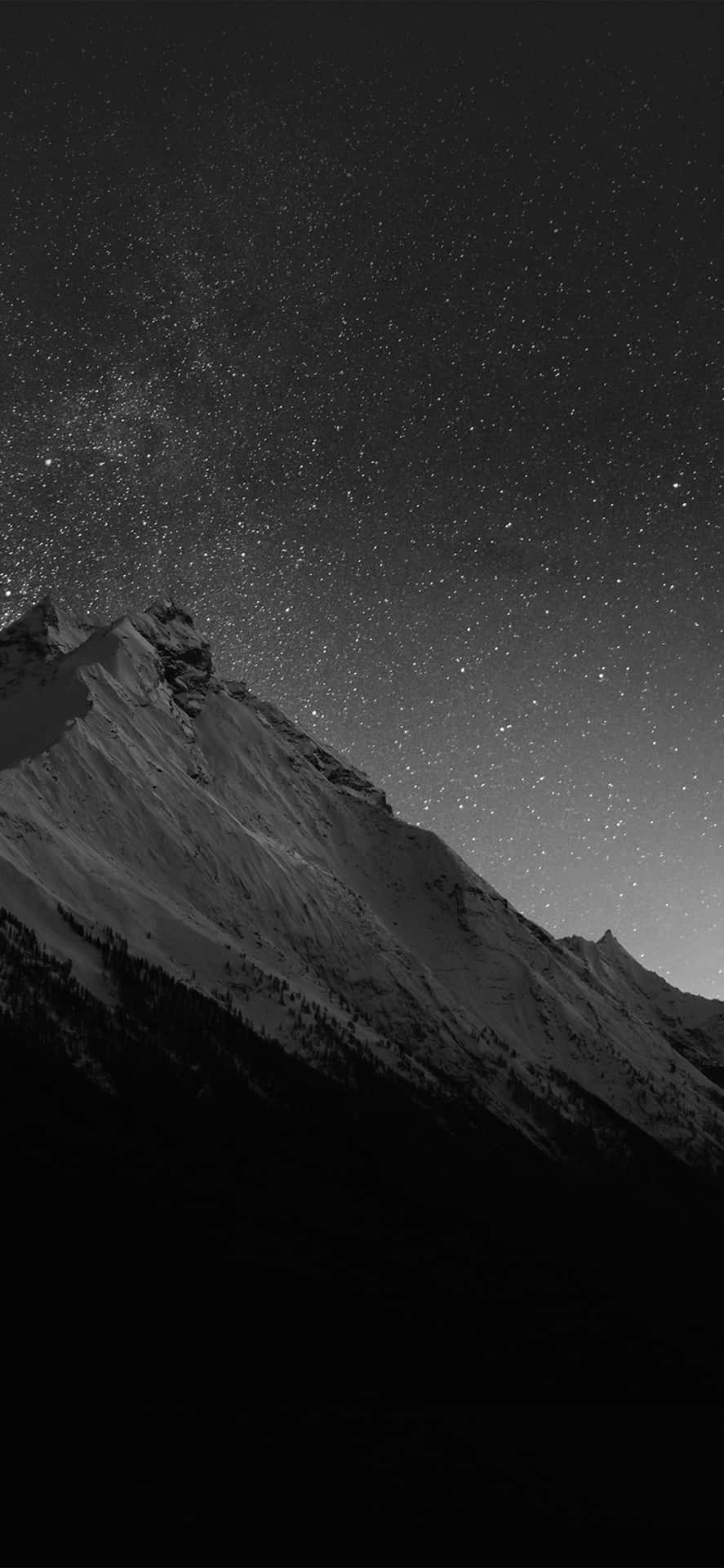  壁紙 — 單色山峰在密集星場下聳立，銀河在頭頂彎曲。