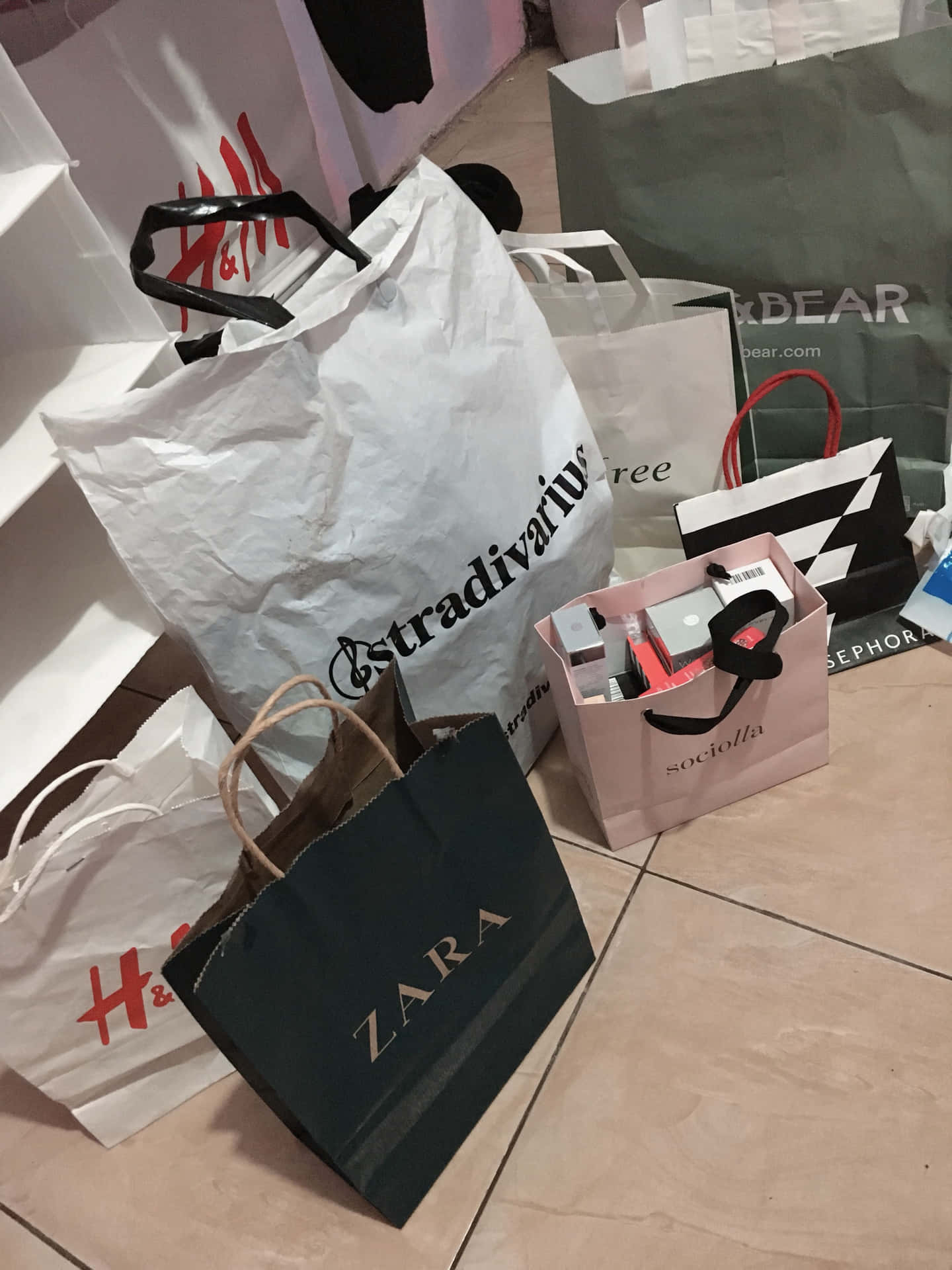  壁紙 — 一堆來自 H&M Zara 和 Sephora 的購物袋放在瓷磚地上，購物後留下的景象。