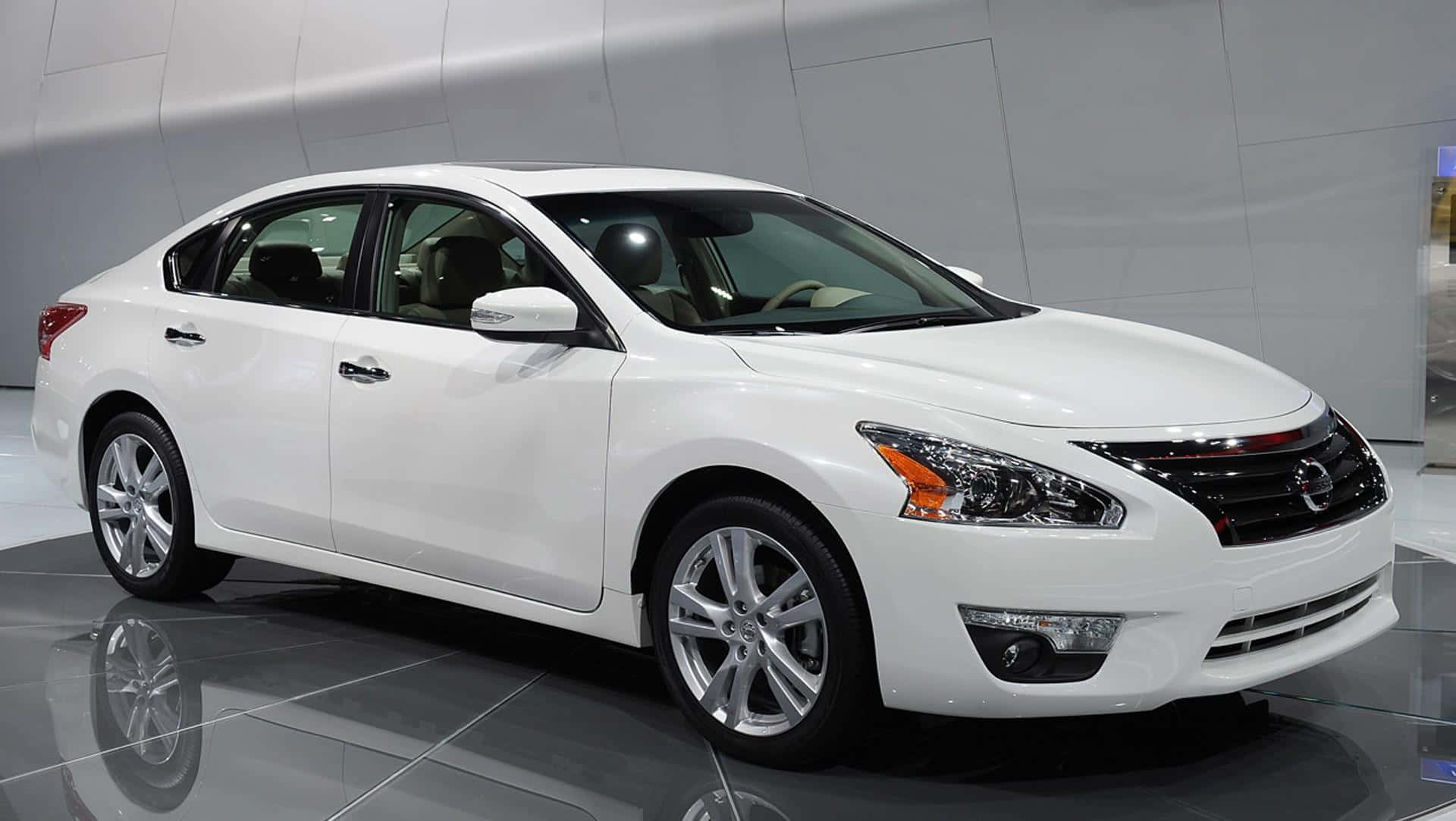 Nissan Altima 桌布 壁紙 — 一輛純白色的日產房車在明亮的燈光下，於反射的展廳地板上閃閃發光。
