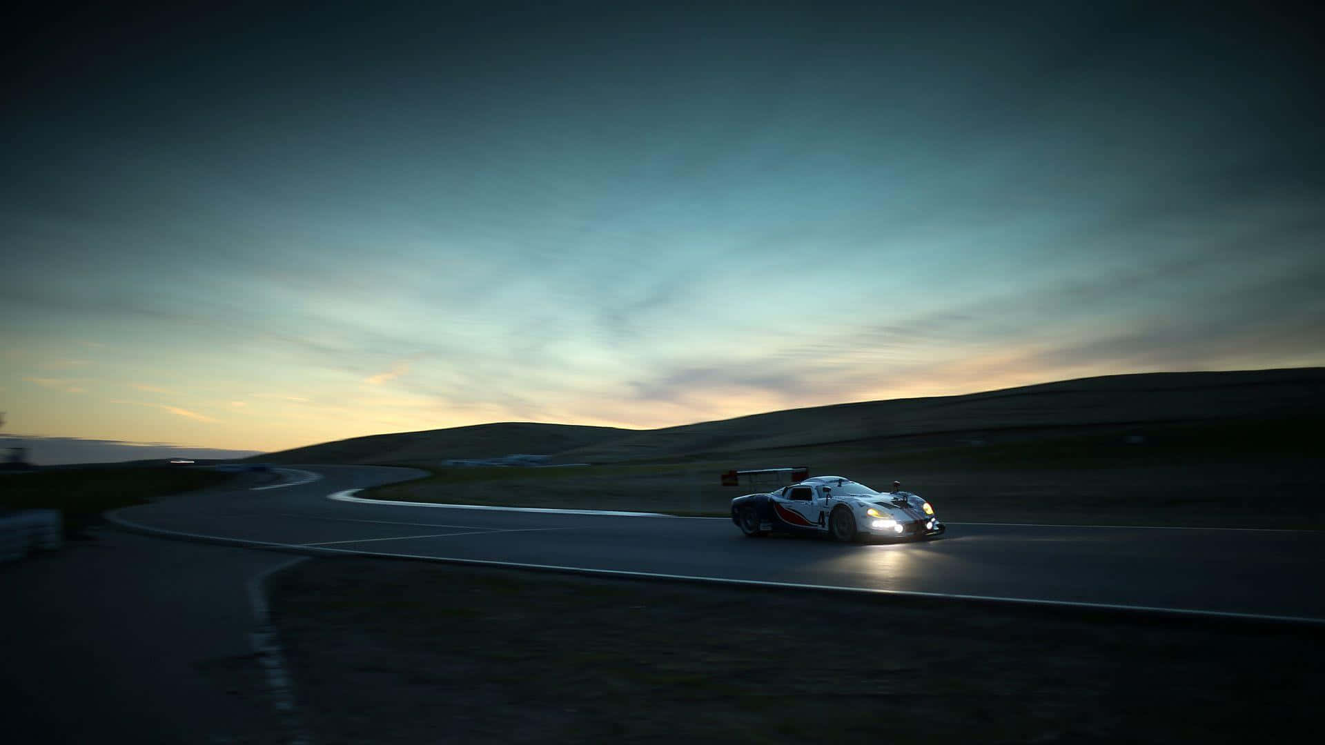 a race car driving down a road at dusk 壁紙