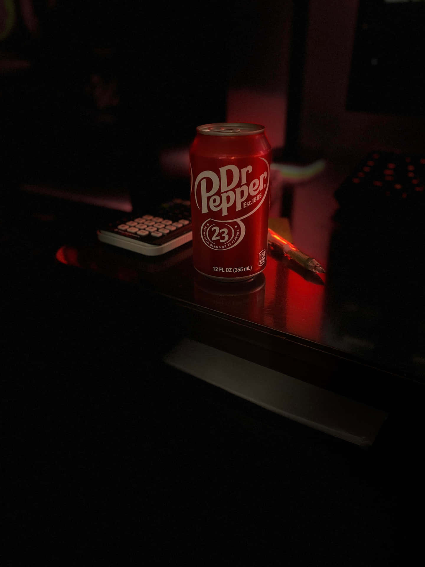  壁紙 — 一個紅色Dr Pepper 23罐在昏暗的桌子上，在鍵盤和遙控器旁邊，在環境光下發光。