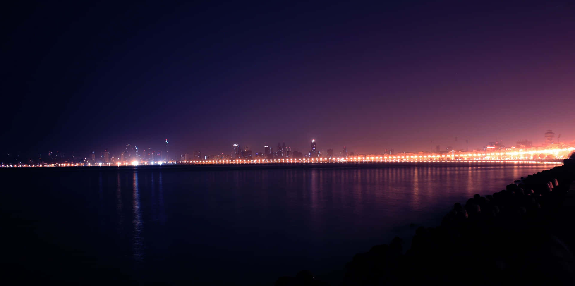 夜晚城市燈光倒映在平靜的水面上，天空呈現紫色。