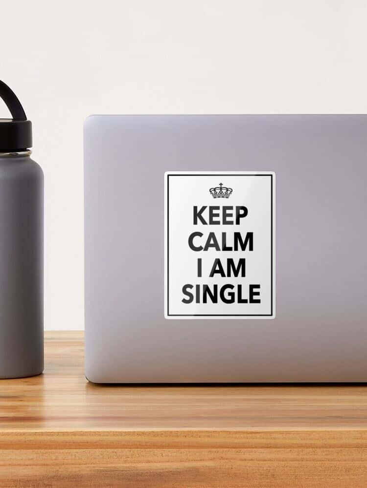  壁紙 — 一部銀色手提電腦貼有「Keep Calm I Am Single」貼紙，旁邊有一個灰色水樽，放在木桌上。