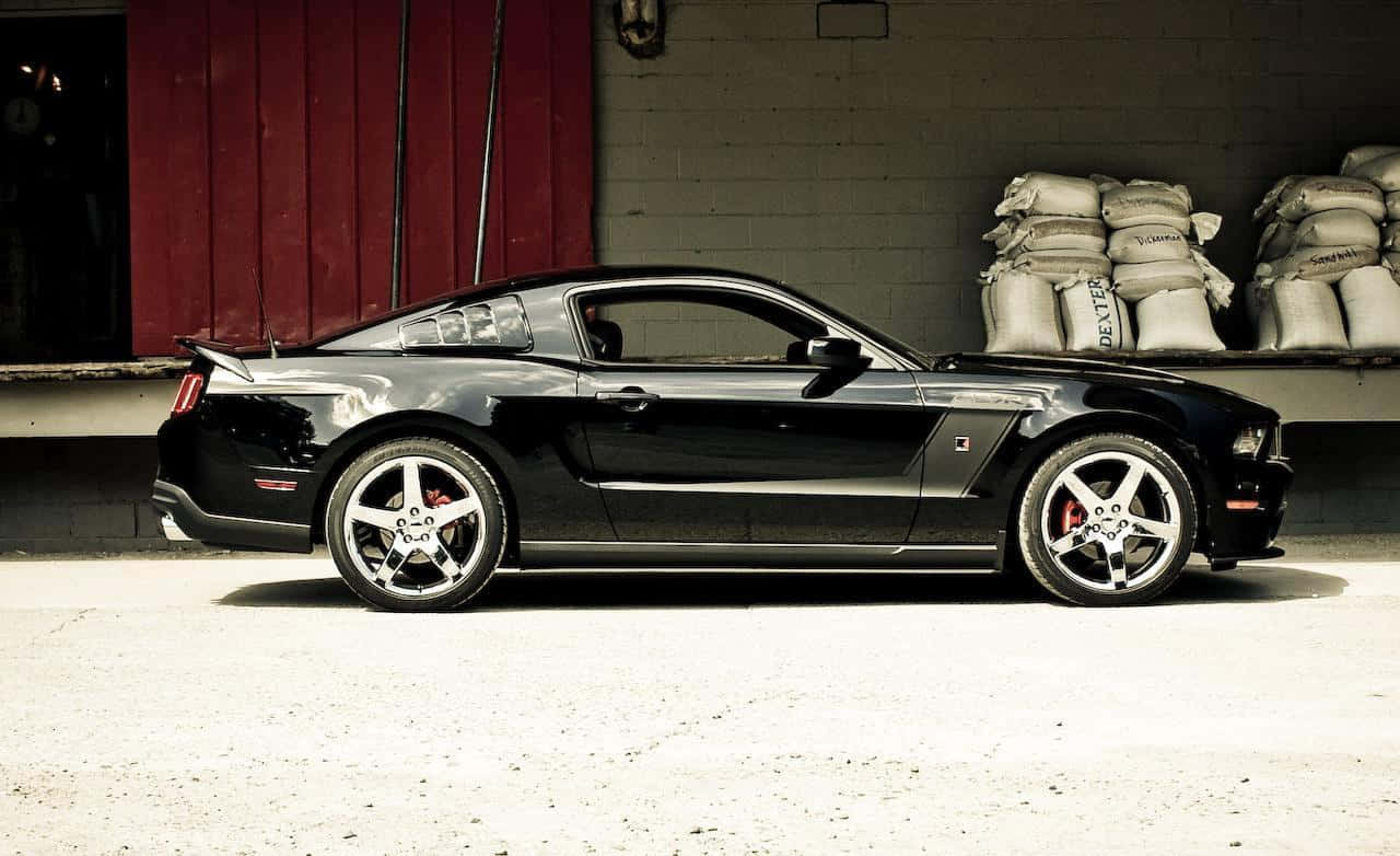 Ford Mustang Roush 桌布 壁紙 — 一架型格黑色福特Mustang跑車停泊在紅色穀倉前，附近有麻袋堆疊。