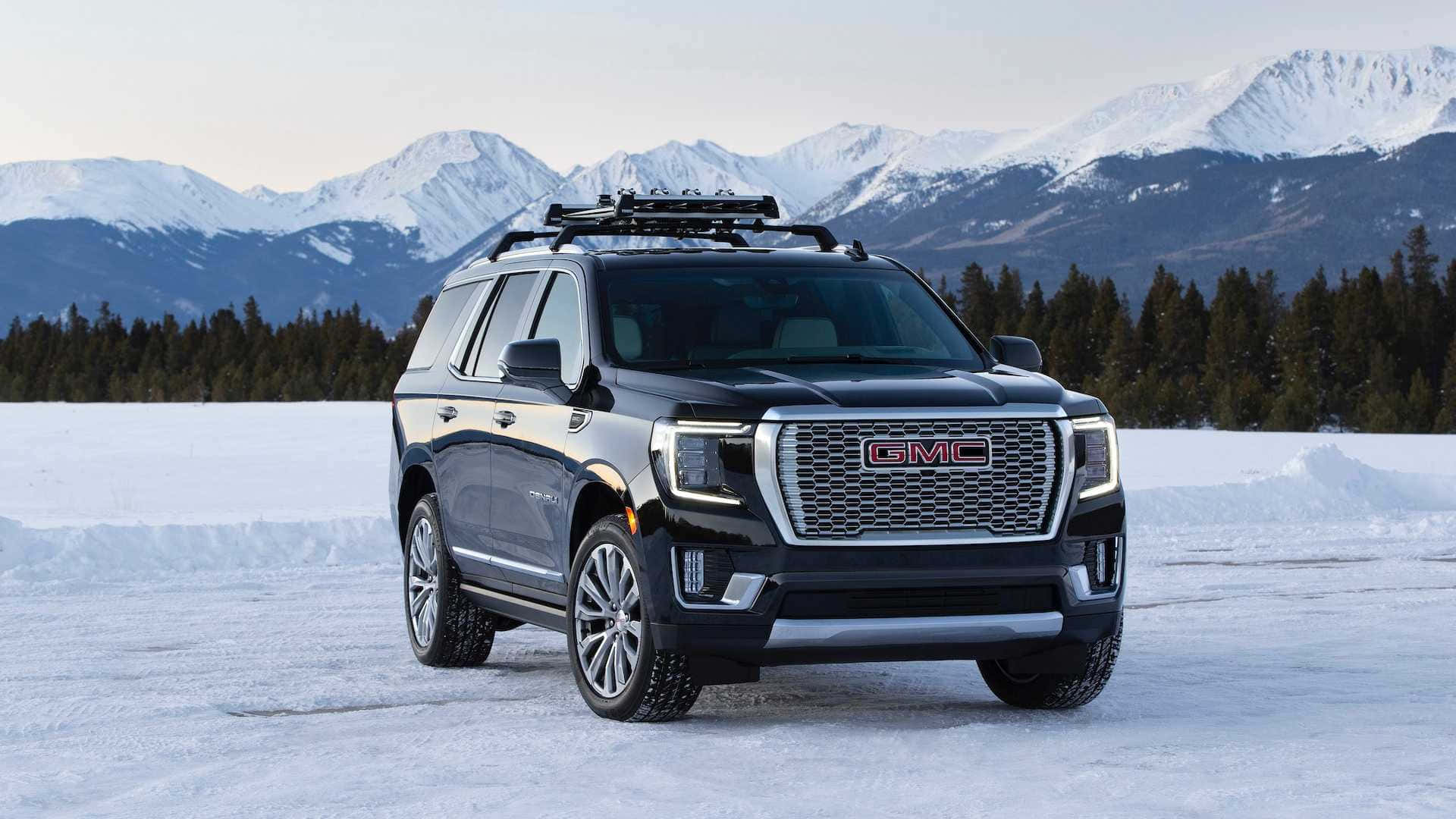 Gmc Yukon 桌布 壁紙 — 一架時尚的黑色GMC Yukon停在冰凍的湖面上，背景是白雪覆蓋的山脈和常青樹。