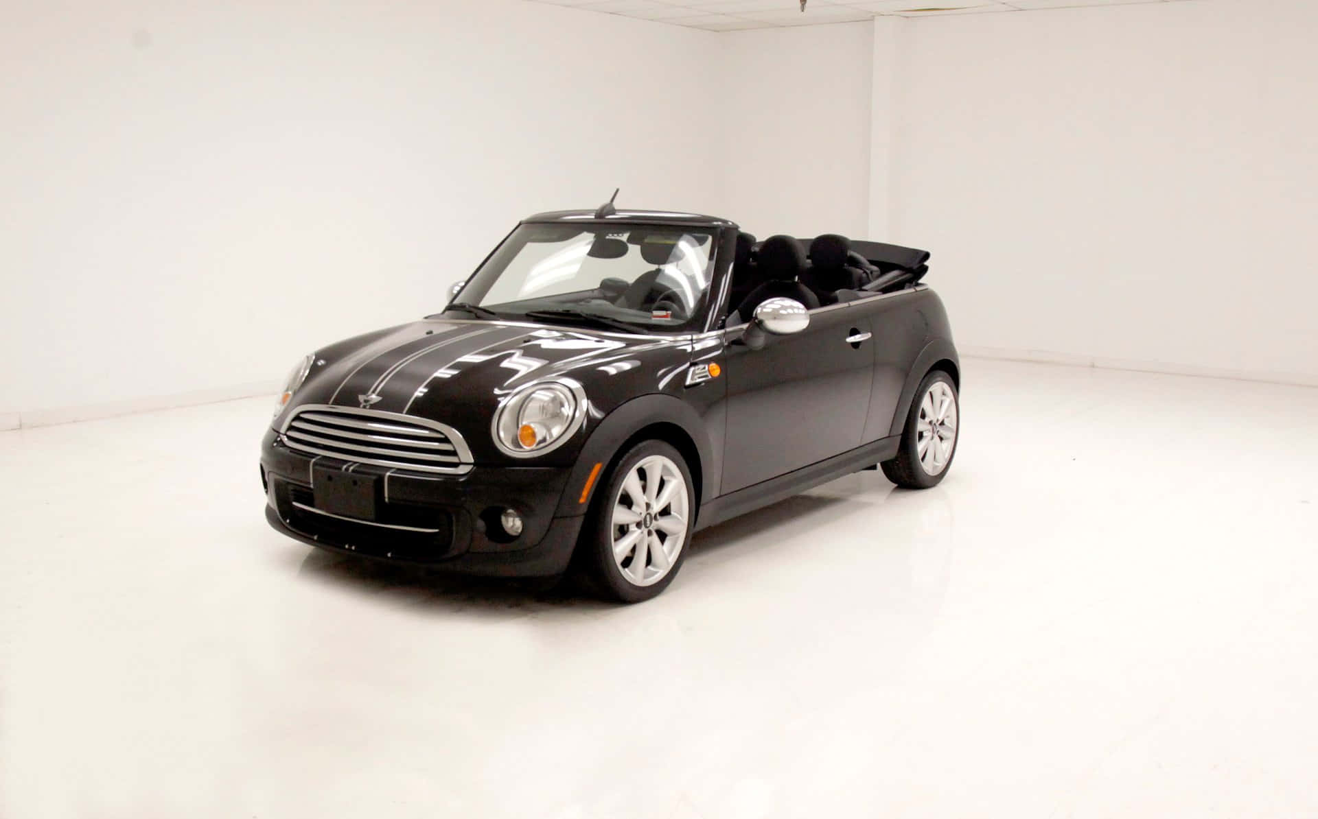 Mini Cooper Convertible 桌布 壁紙 — 一輛時尚的黑色Mini Cooper開篷車，帶有白色賽車條紋，停在明亮的白色攝影棚空間中。