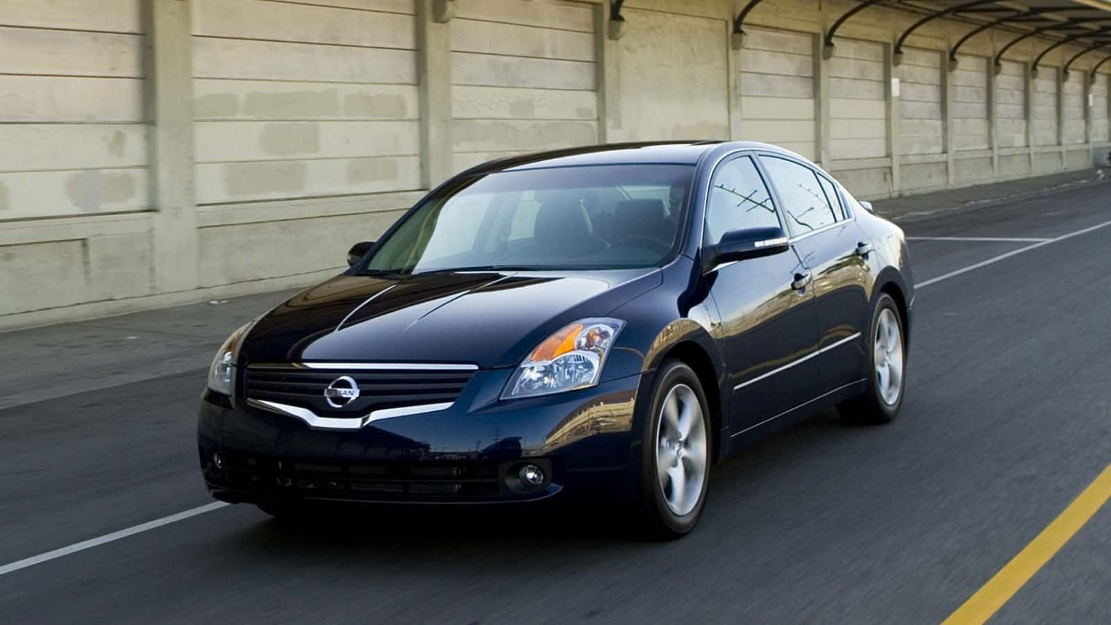 Nissan Altima 桌布 壁紙 — 一架流線型黑色日產房車在陽光普照的城市道路上行駛，經過混凝土天橋下方。