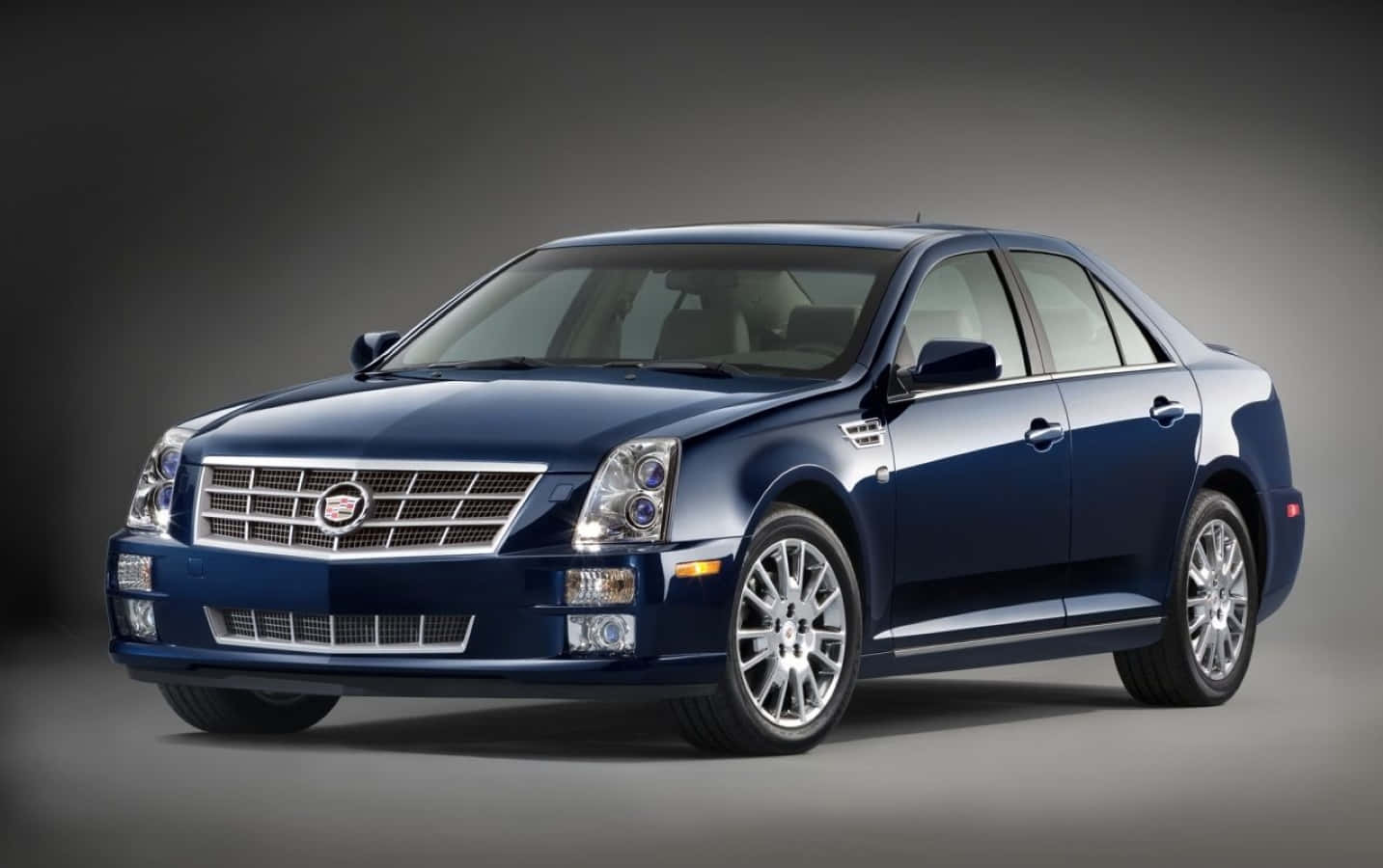 Cadillac Cts 桌布 壁紙 — 時尚的藍色凱迪拉克轎車在工作室燈光下閃耀，帶有鍍鉻飾條和合金輪圈。