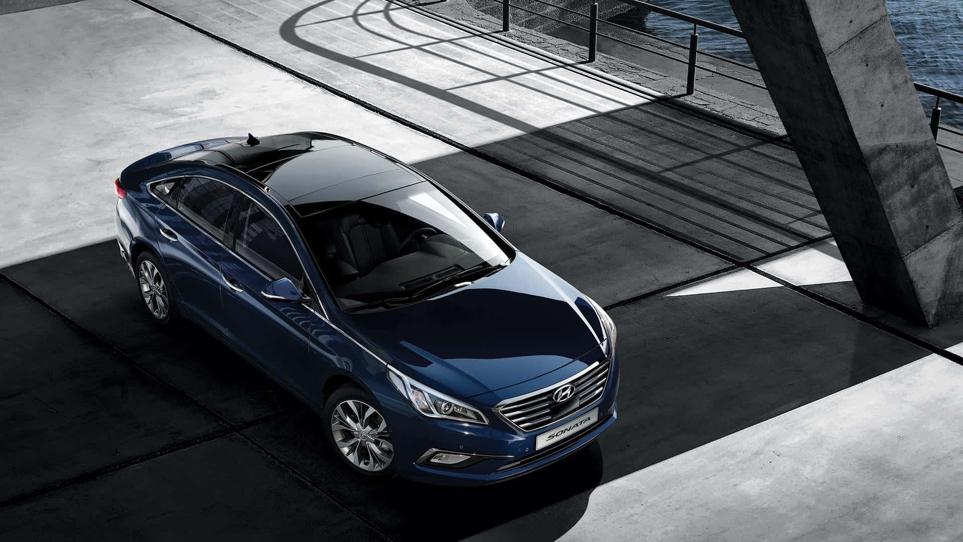 Hyundai Sonata 桌布 壁紙 — 一架時尚的藍色轎車停泊在現代混凝土碼頭上，帶有幾何陰影和背景的水面。